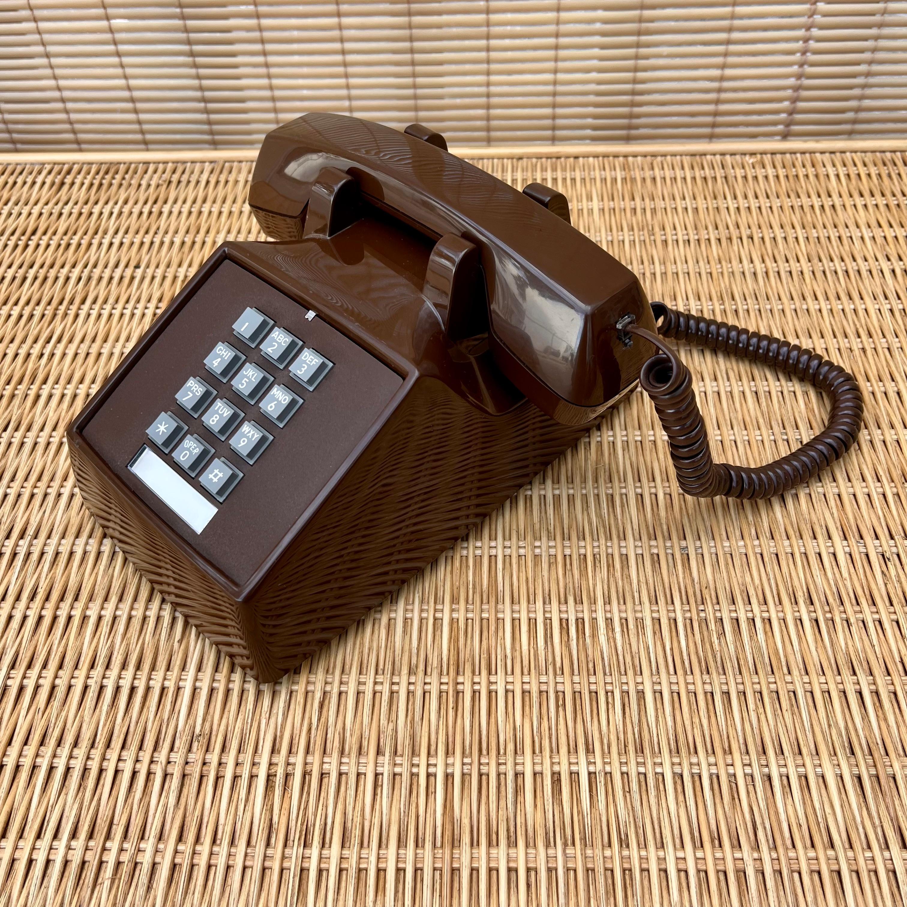 Téléphone de bureau vintage à touches de couleur chocolat. Circa 1980
Le corps est brun chocolat brillant et les boutons gris contrastent. 
La base est dotée de pieds en caoutchouc pour éviter de glisser.
Le cordon d'origine (qui se branche sur