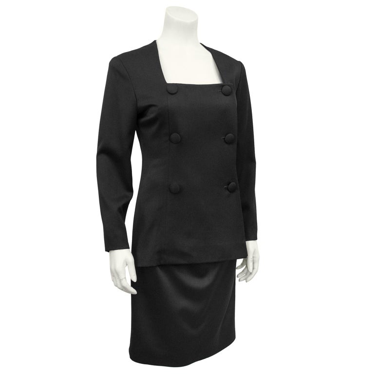 1980s black fine wool Christian Dior cocktail dress. The dress looks like a double breasted tuxedo jacket and pencil skirt ensemble from the front, and a dress from the back. Deep cut square neckline and long sleeves. Elegant sweep to the front of