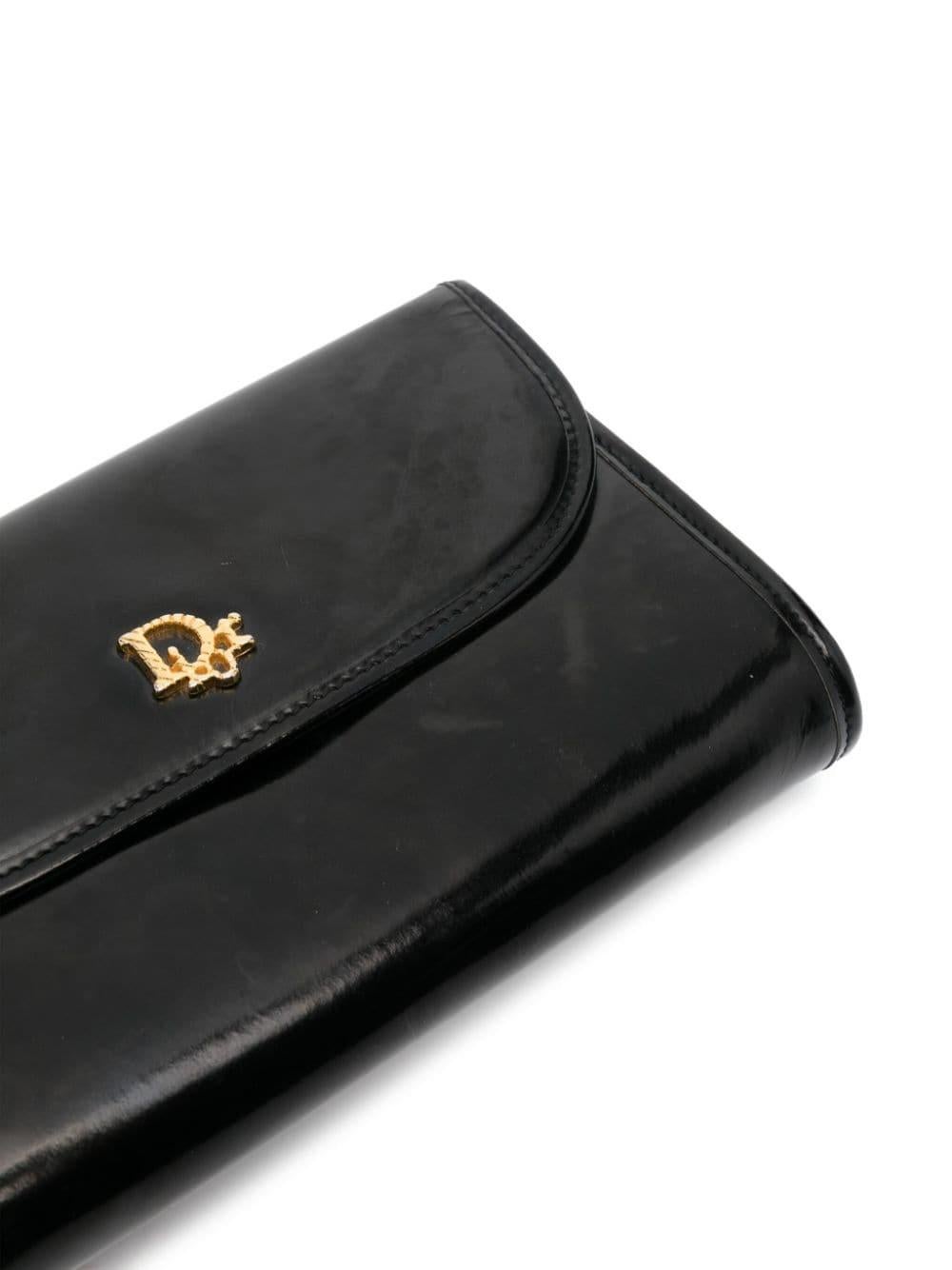 1980s Christian Dior black leather shoulder bag featuring a shiny finishing, front snap closure opening, a signature front 'Dior' plaque, a gold-tone chain-link shoulder strap, an inside gold tone logo stamp, gold-tone hardware, a foldover top with