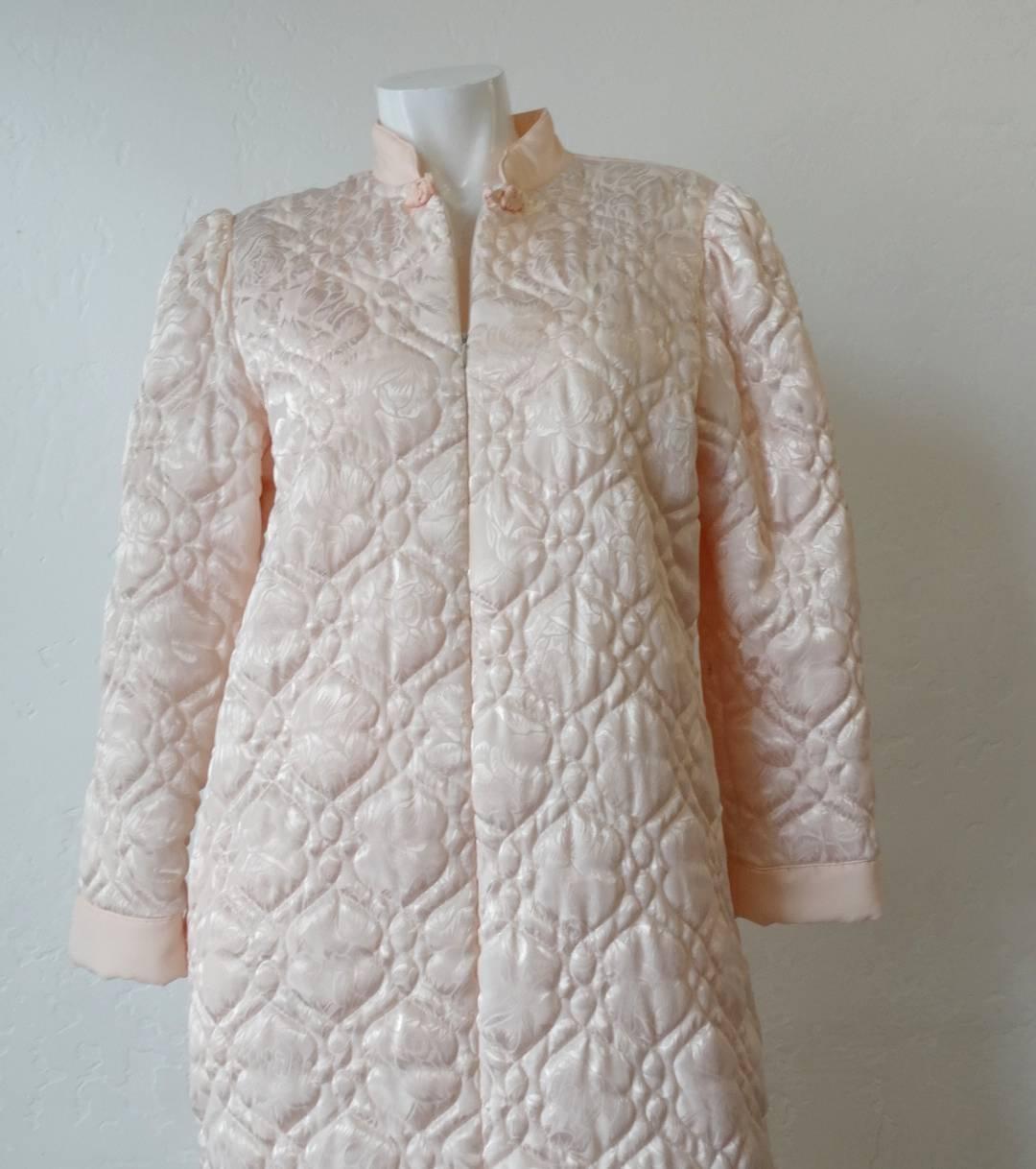 Rock the pajamas-all-day look with this adorable 1980s Christian Dior coat! Made of a soft pink satin, stitched intricately with a quilted pattern. Mandarin style collar, zips all the way up the front with a hidden zipper. Long sleeves with slightly