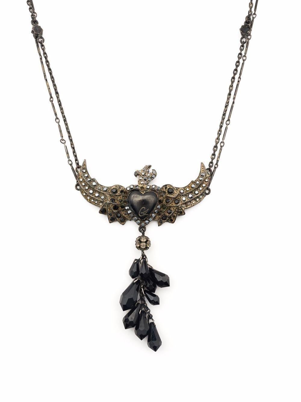 Collier Christian Lacroix des années 1980 en forme de cœur d'oiseau avec pierre noire/bronze, détails de perles, motif en forme de cœur, chaîne à maillons de câble, fermeture à griffes de homard, chaîne à longueur réglable.
Longueur ouverte  14.6
