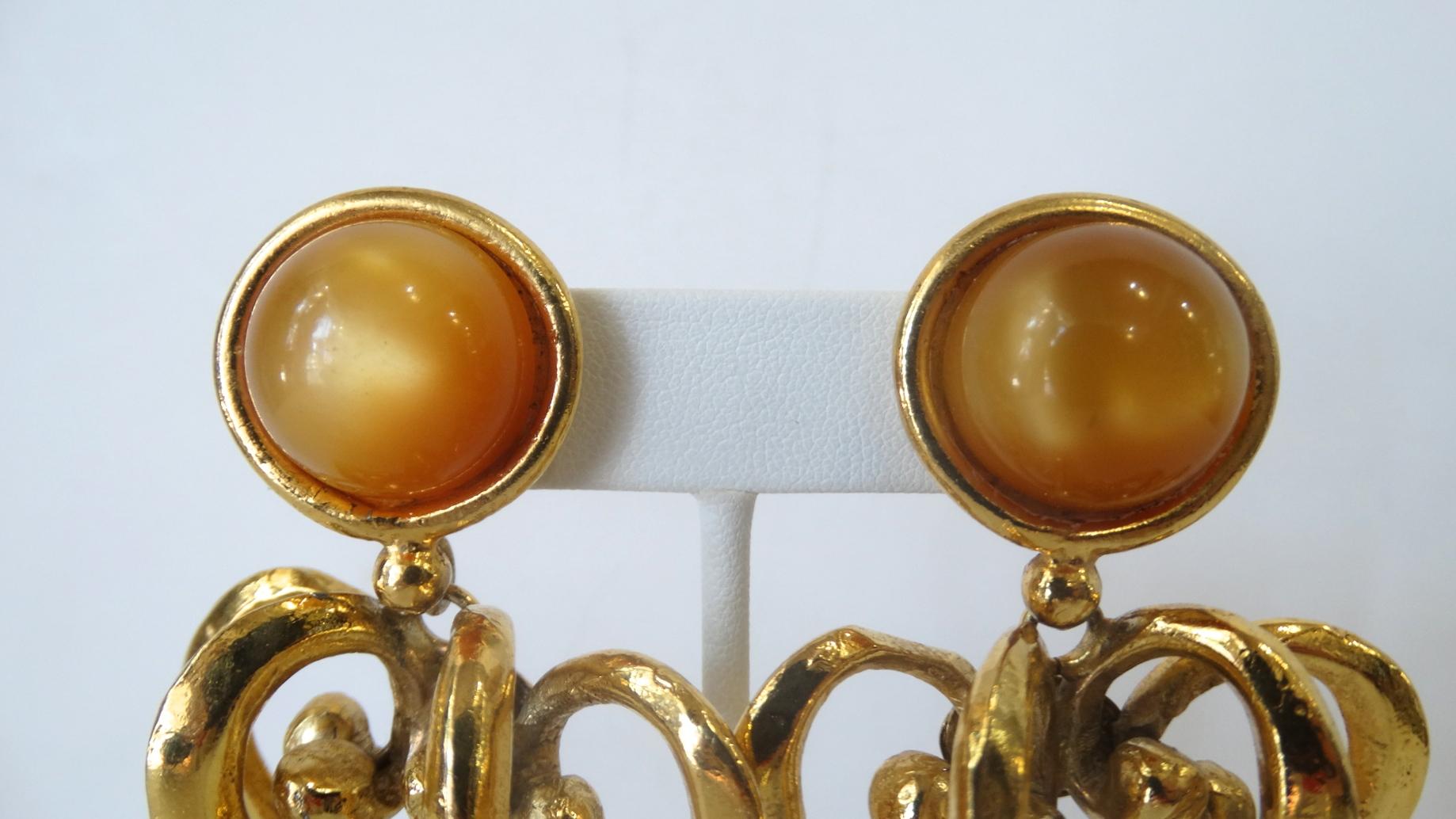 The Most Amazing Lacroix Earrings Are Here! Circa 1980s, these gold plated drop earrings feature two tiered Baroque style scroll hearts and a small amber colored bead hanging from the end. Clip on closures include an amber colored acrylic gem as the