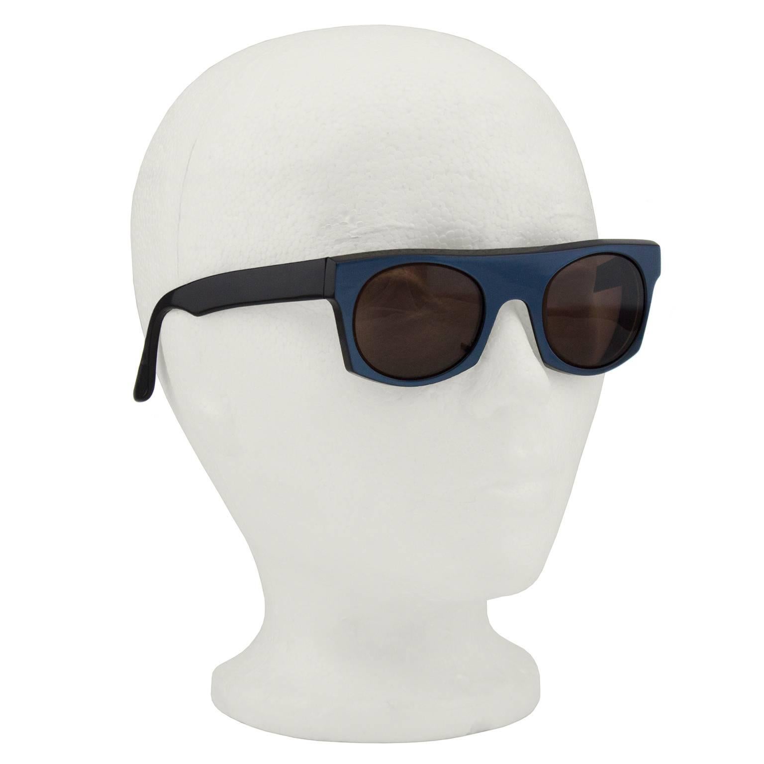 1980s Claude Montana by Alain Mikli midnight blue metallic sunglasses with black arms. Interior is reversed with metallic blue arms and black around back of lenses. Black lenses with slight surface scratching. White branding stamped on interior of