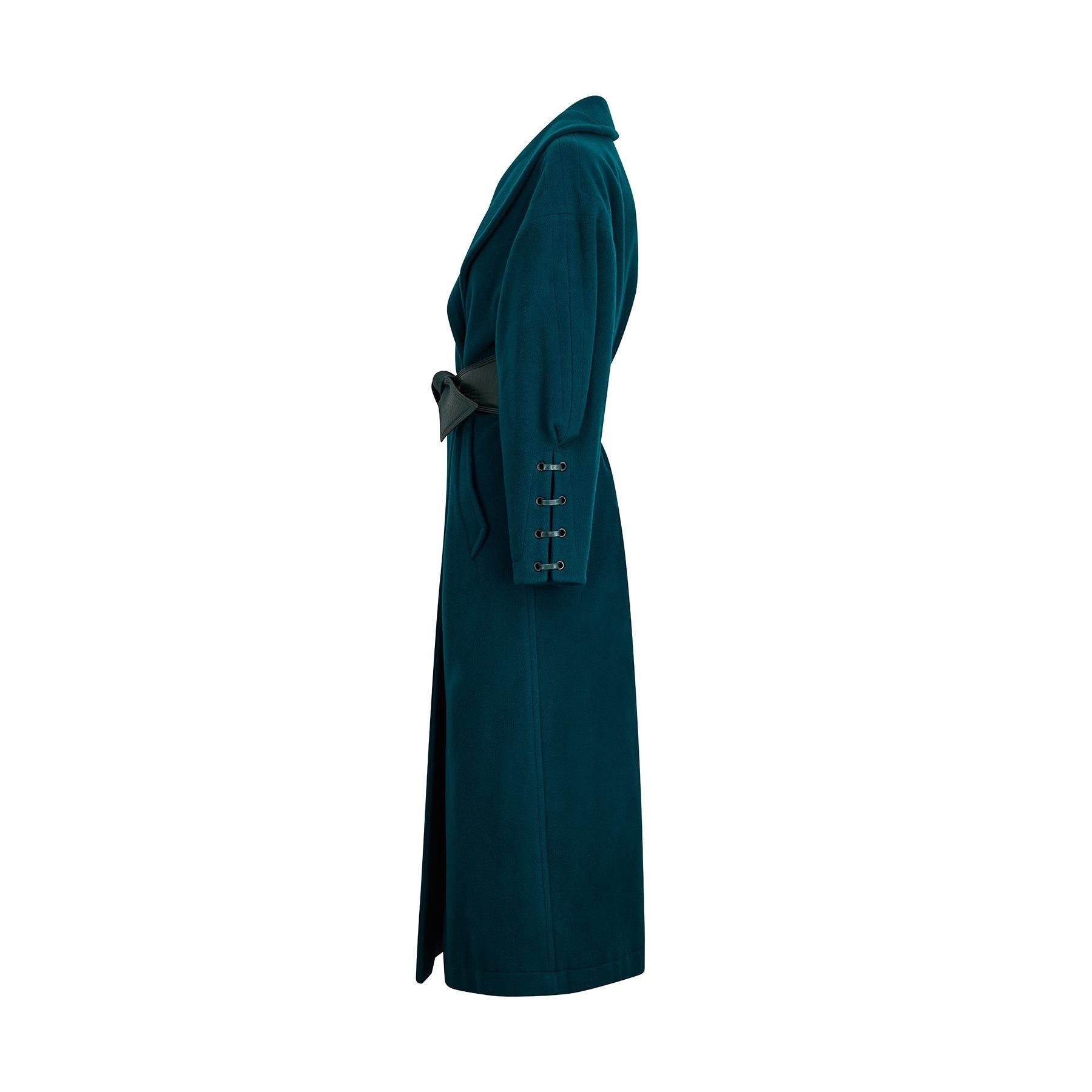 1980s or early 1990s Claude Montana wool coat in a lovely shade of dark teal, almost forest green. It has a wide crossover collar and fastens with a soft leather effect belt in a matching green shade. The sleeves are relaxed through the shoulder and