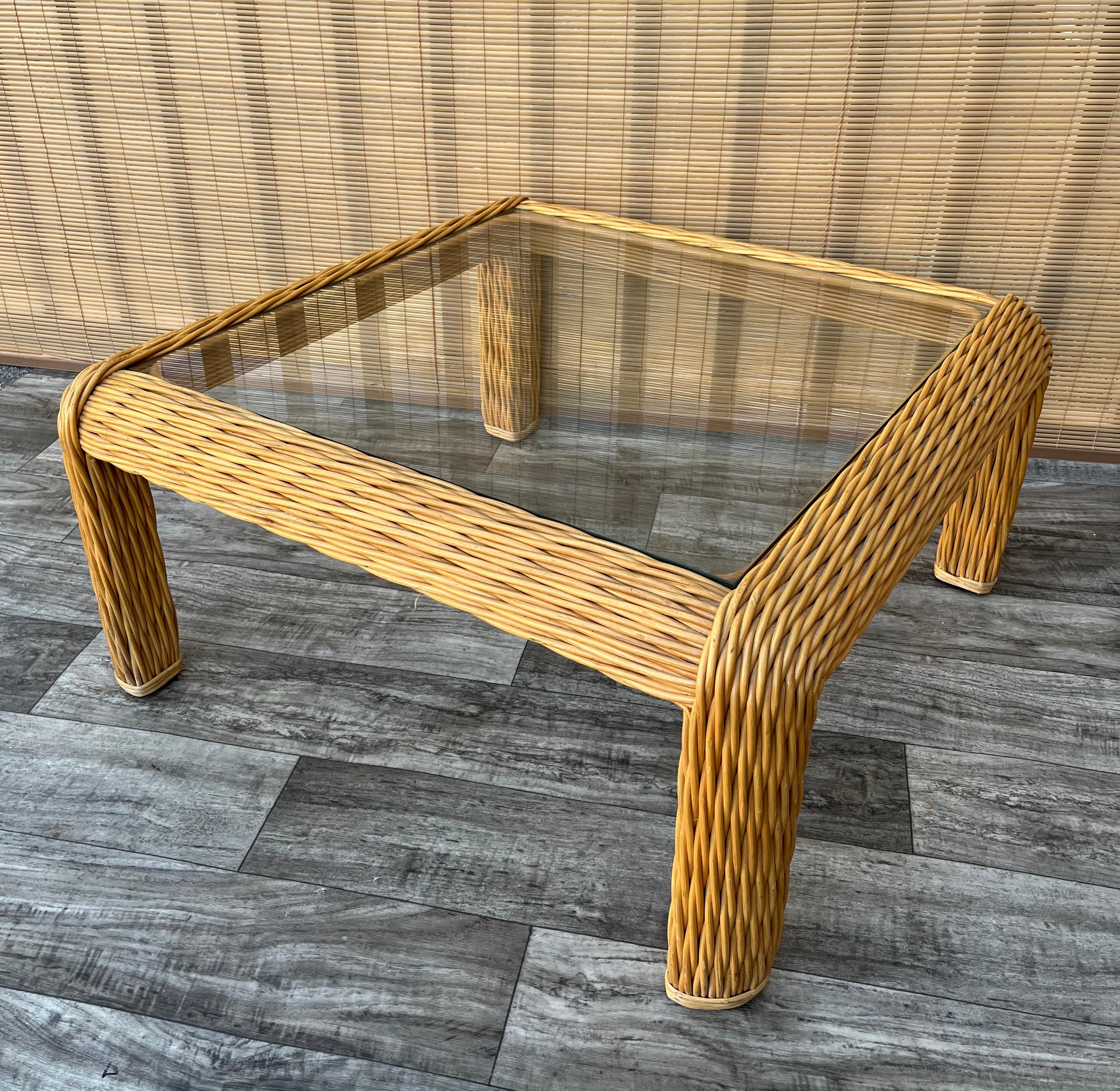 Vintage Coastal Style Braided Pencil Reed Rattan Coffee / Cocktail Table in the McGuire style. Circa 1980s.
Features sophisticated curves, an elaborated braided pencil reed construction and an a glass top.
In excellent original condition with
