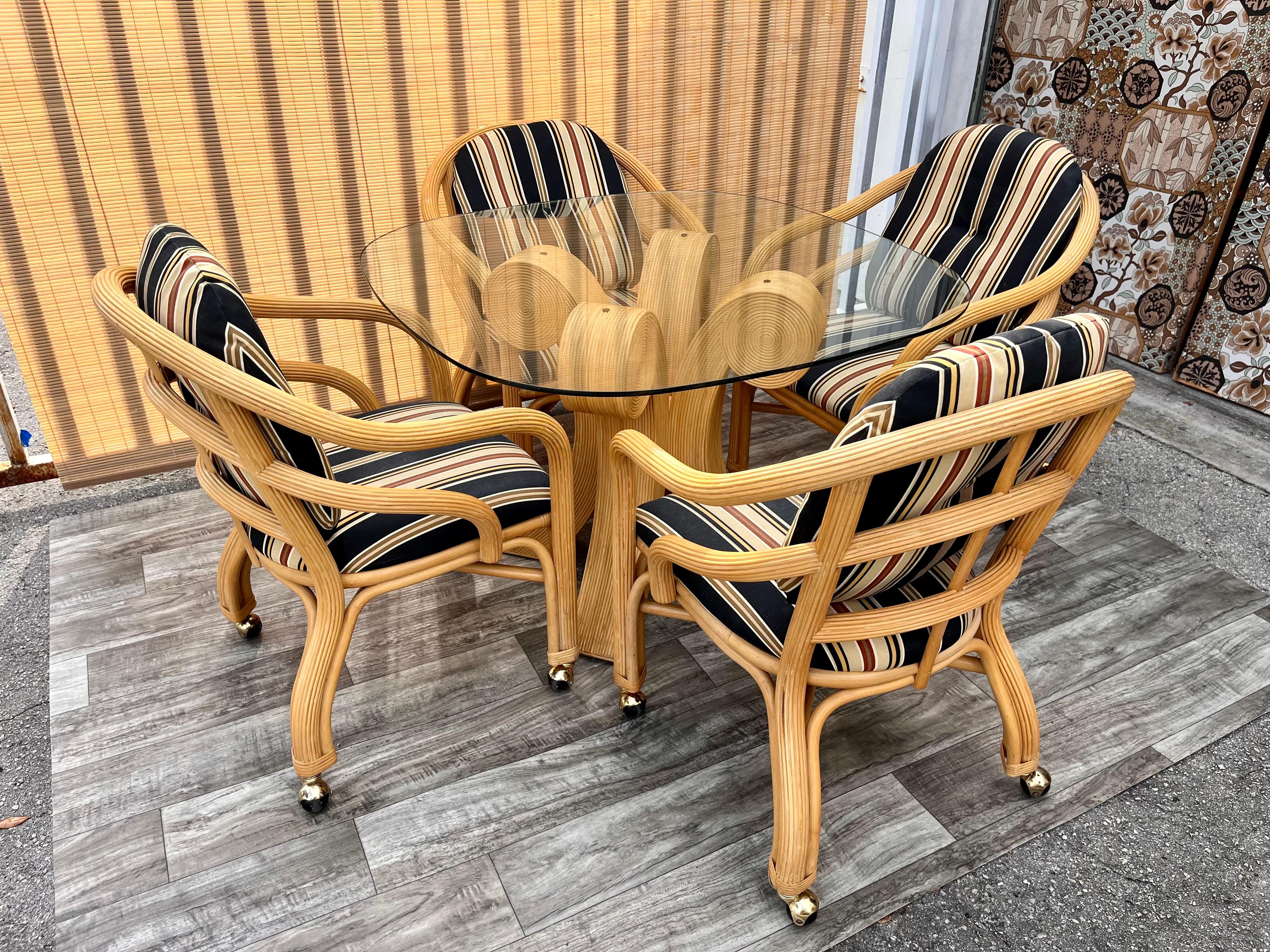 Vintage 5 pieces coastal style pencil reed dining / game set. Circa 1980s 
The Table features an intricate Pencil Reed Pedestal in a natural finish with a round beveled glass top that comfortably seat 4 guests. 
The chairs feature come with what