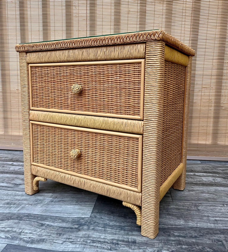 A vintage Hollywood regency / coastal style wicker nightstand by Henry Link for Lexington Furniture. Stamped 1984. 
Features two spacious drawers with round handles, a beautiful braid detail around the top edges, and a removable glass top. 
In