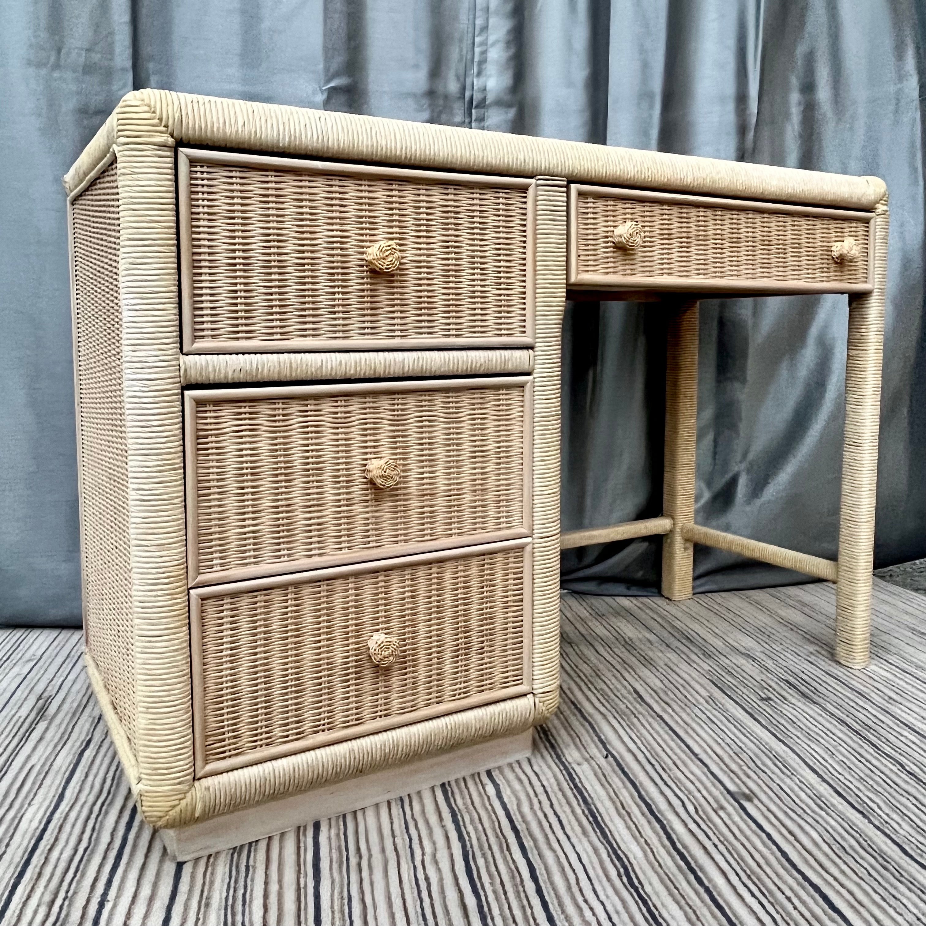 Vintage Hollywood Regency coastal style Wicker vanity / writing desk by Broyhill Furniture. Circa 1980s. 
Features four spacious drawers with rattan handles, a body wrapped in a beautifully weaved wicker with a corded wrapped trim detail around all
