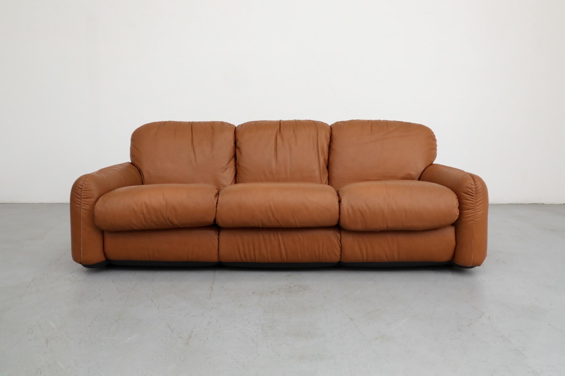 Bellissimo divano a 3 posti in pelle cognac disegnato dall'architetto italiano Arrigo Arrigoni per Busnelli, anni '80. I cuscini sono riempiti con schiuma a bassa densità, per garantire un'esperienza di seduta ultra-morbida e bassa. Questo divano è