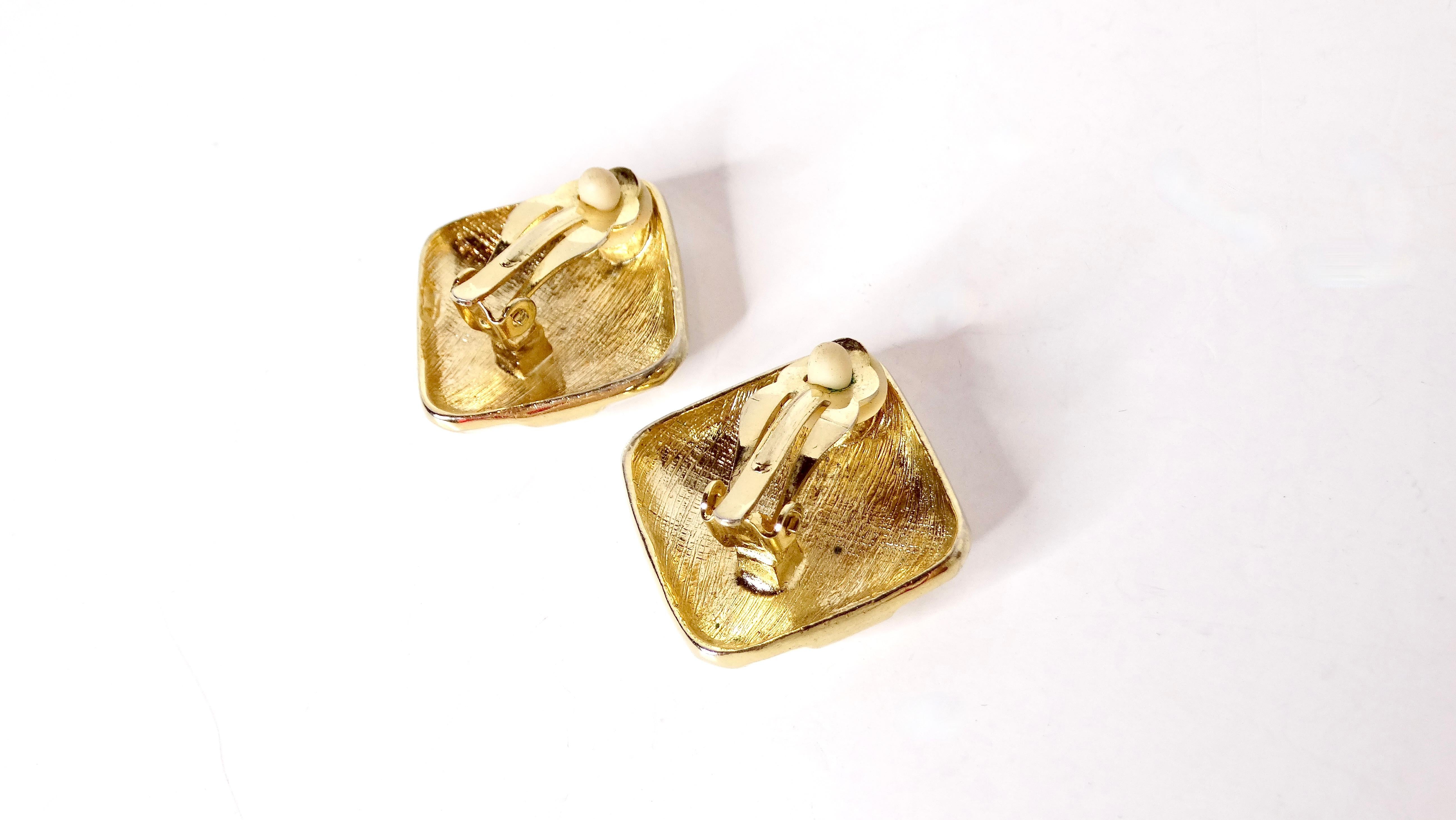 Adopta la atrevida e icónica estética de los años 80 con estos destacados Pendientes de clip cuadrados gruesos con esmalte crema y baño de oro de 14k. Estos pendientes presentan un diseño único entrecruzado sobre una elegante base cuadrada, que