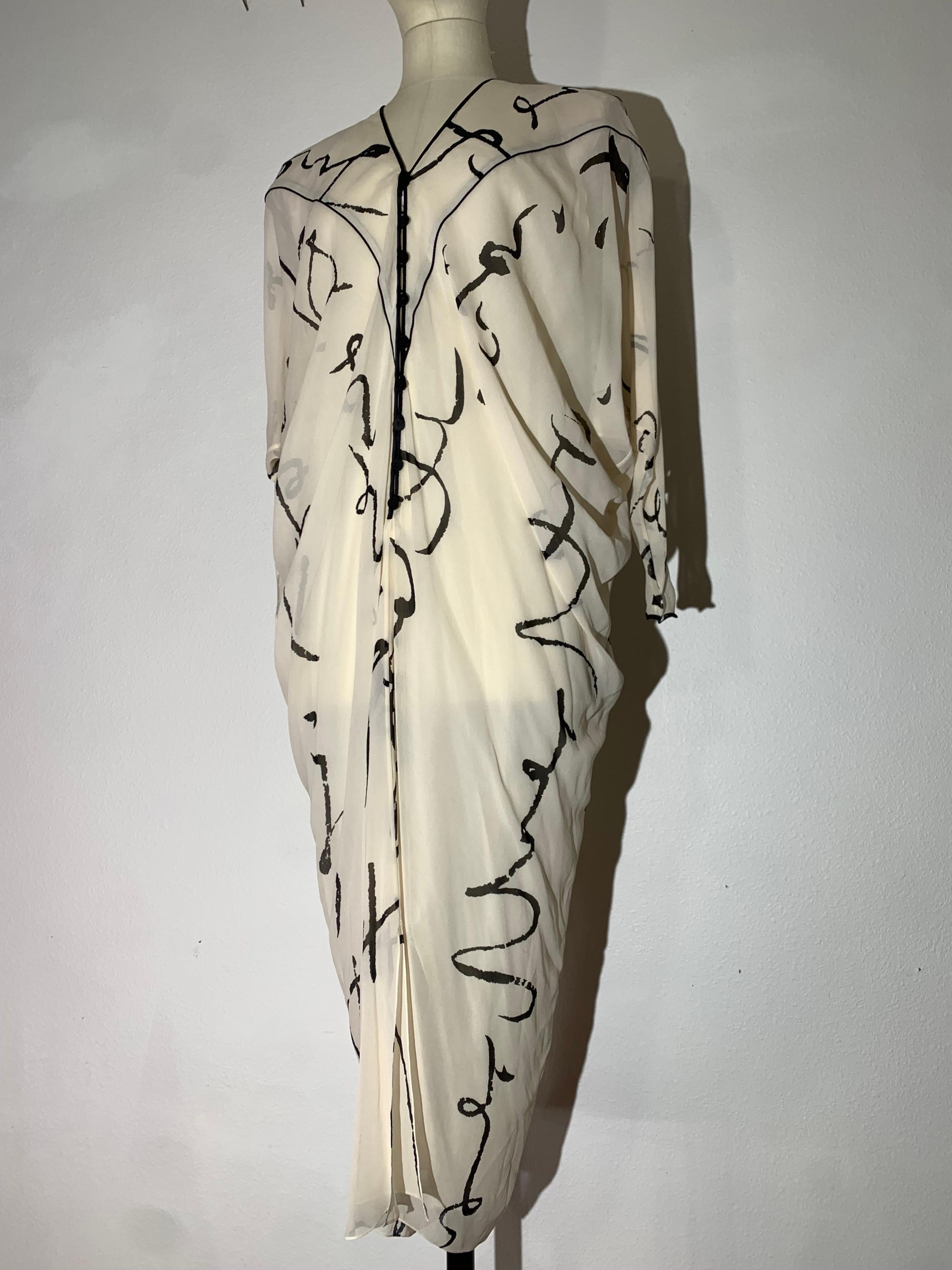 Abito caftano anni '80 in chiffon di seta color crema con stampa calligrafica nera:  Vestibilità drappeggiata con maniche Dolman, bottoni e profili neri sulla chiusura anteriore. Completamente foderato con morbidi pad strutturati. Appesantito sul