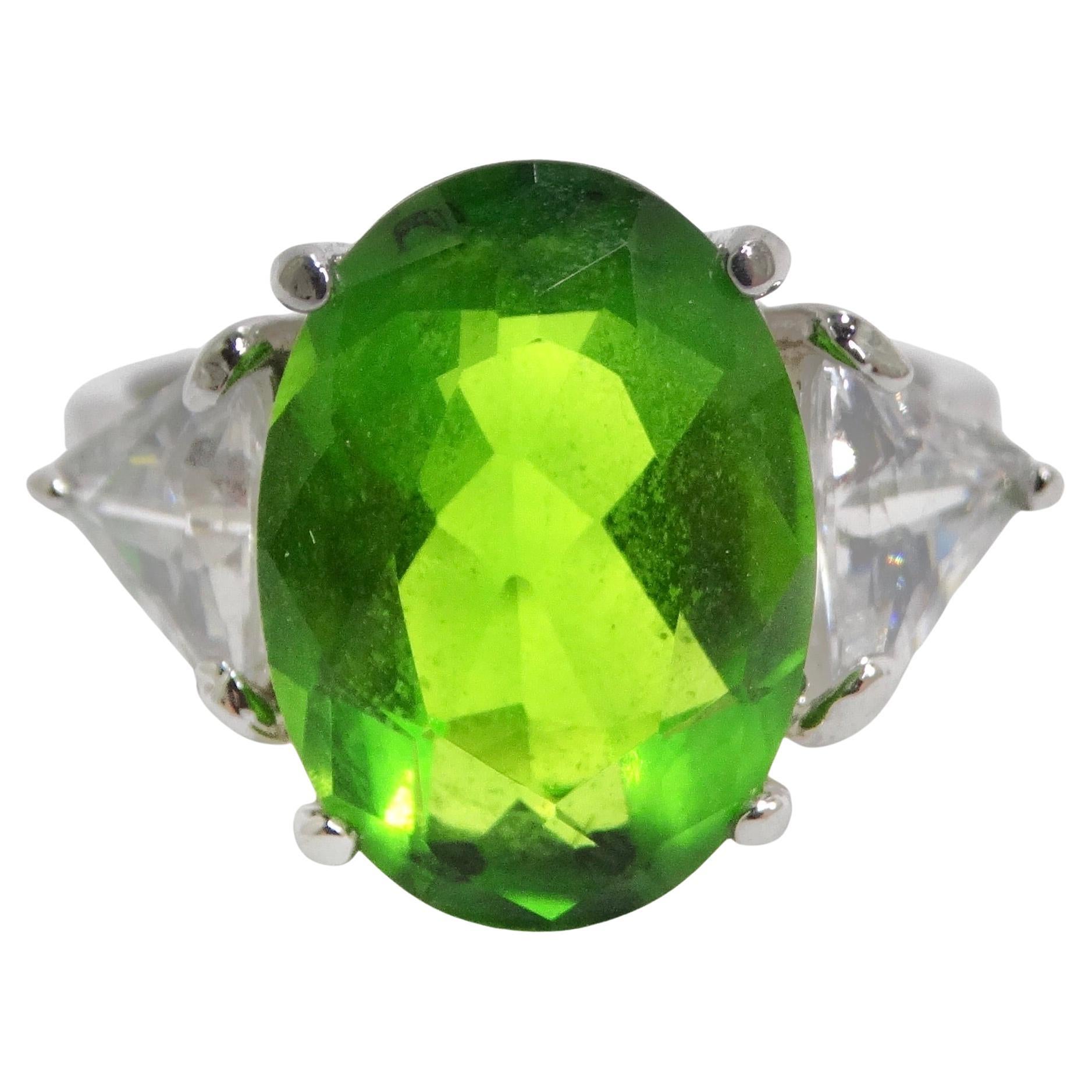 Step into the captivating world of the 1980s with our exquisite custom silver plated ring. This unique piece showcases a delicate silver-plated band, harmoniously paired with a vibrant green synthetic tourmaline at its center, surrounded by clear