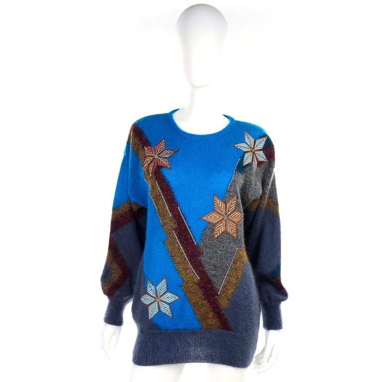 This is a gorgeous vintage sweater designed by Margaretha Ley for Escada in the 1980's.  This pullover style mohair blend sweater is in a brilliant blue with gray, bronze and green designs including star shaped snowflakes!  This sweater has its