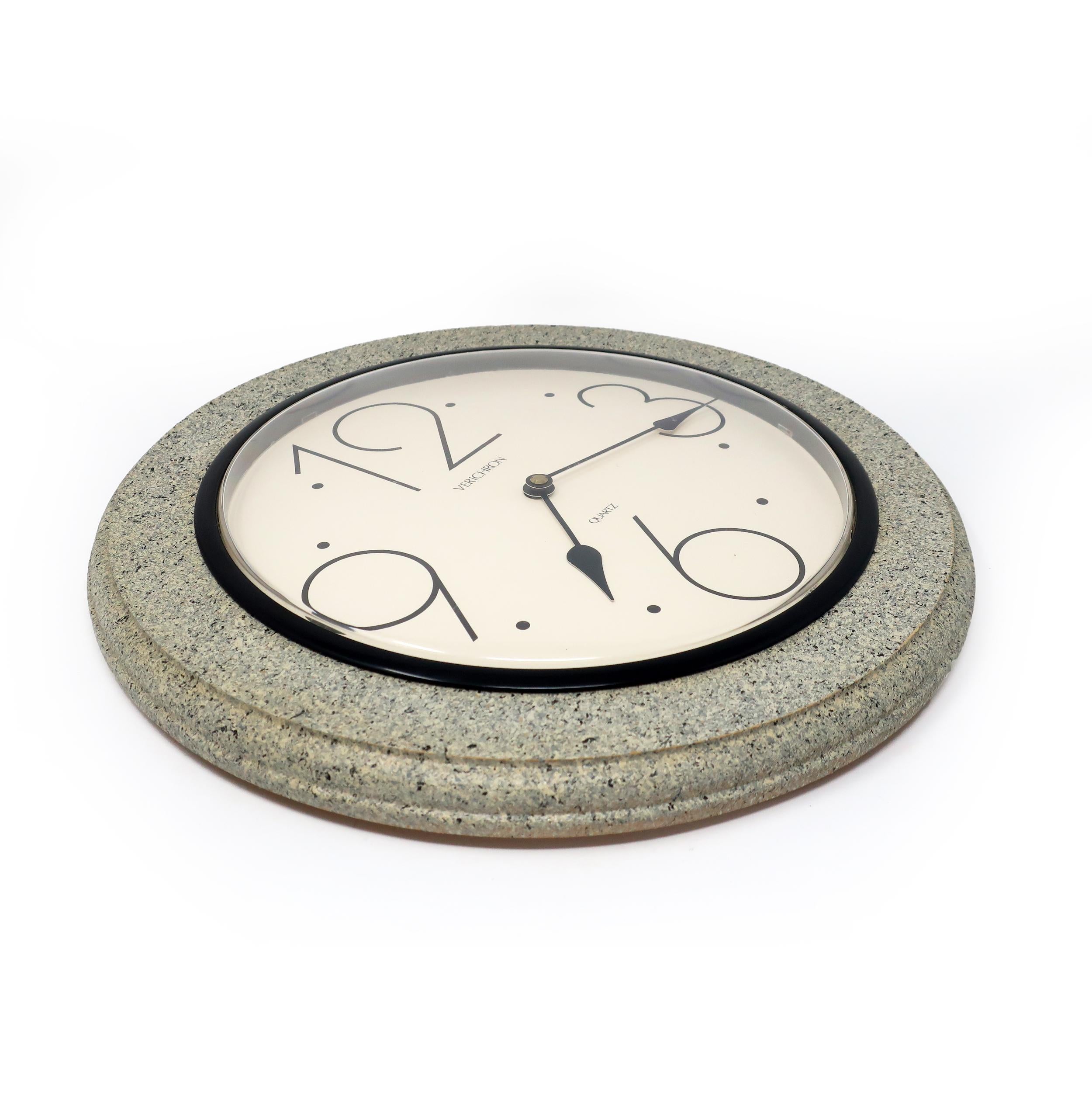 A vintage 1980s postmodern styled wall clock by Verichron. The clock's face is off white with large Art Deco-styled numbers and black hands. Surrounding the clock's face is a black ring and a gray and black speckled wood ring.

In good vintage