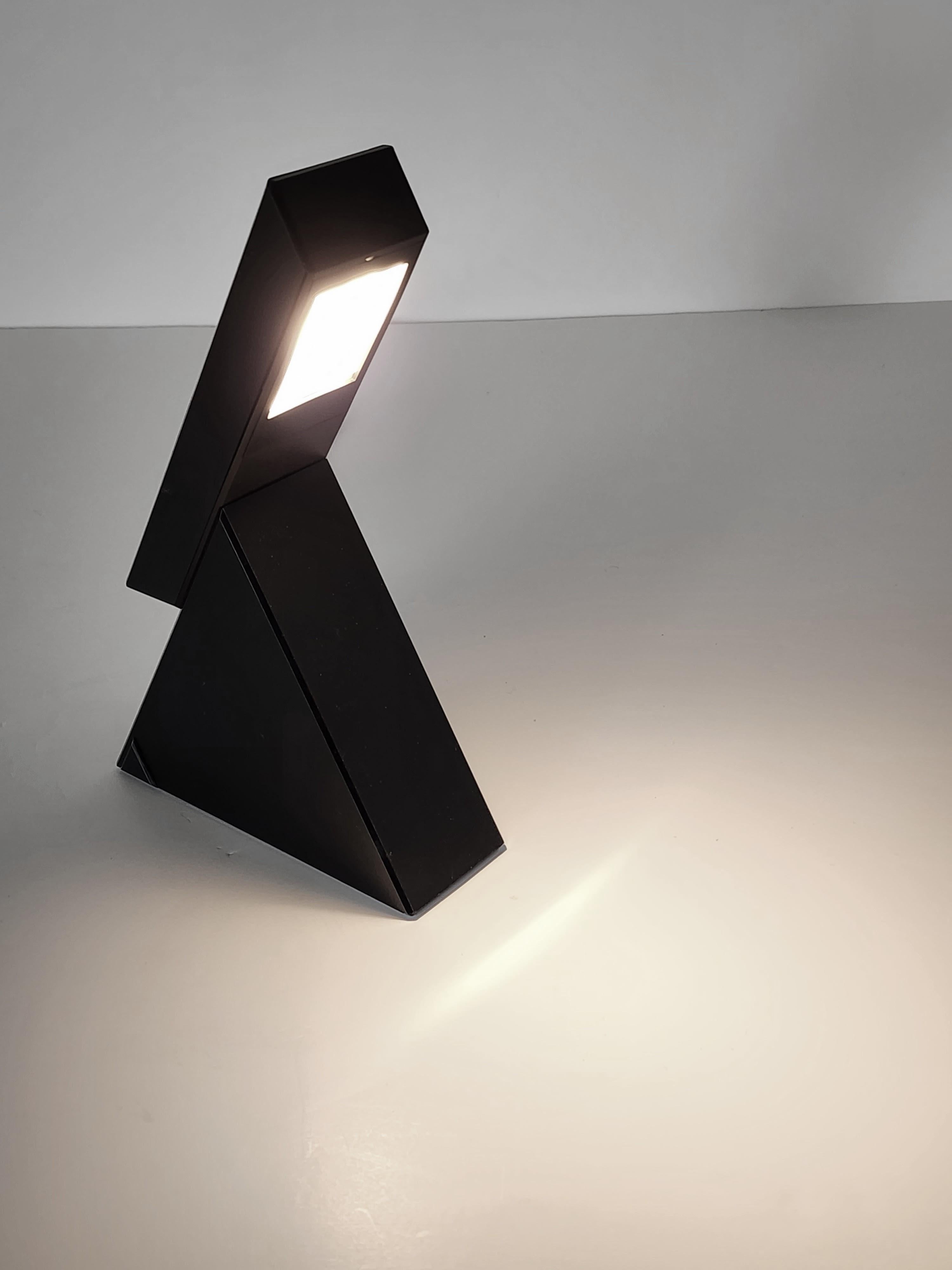 Bold and ingenious design from Mario Bertorelle for JM RDM , Italy . 

The light switch on/off by sliding the flat part on the back  pyramid shaped base . See video . 

Plus it has two intensity , maximum power when fully extended ,  half power when