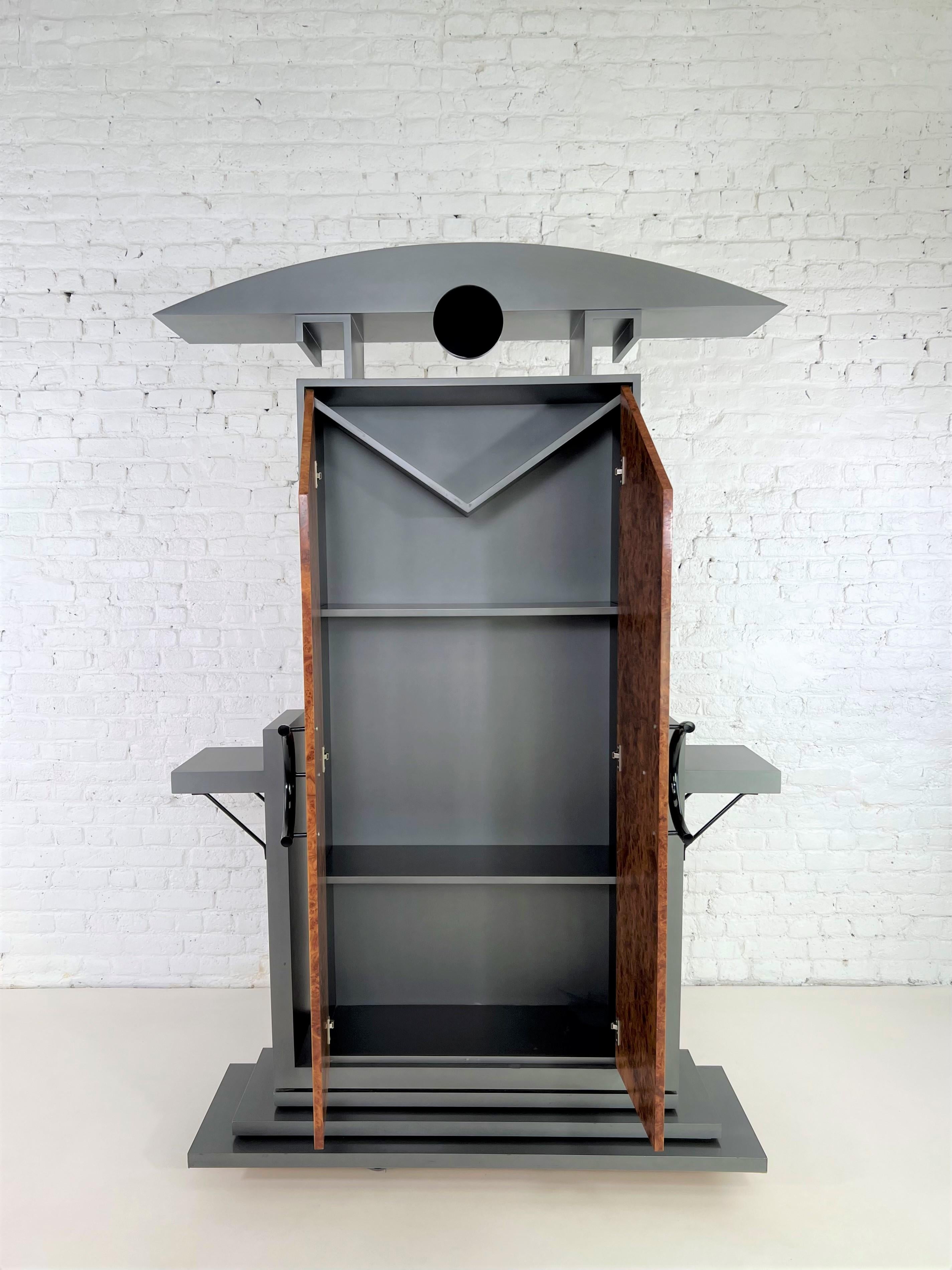 1980s Italian Design and Memphis style walnut burlwood and grey lacquer cabinet in a post modern Pagoda style shaped composed of grey lacquered wooden base, walnut burlwood doors opening on shelves and black metal finishes.