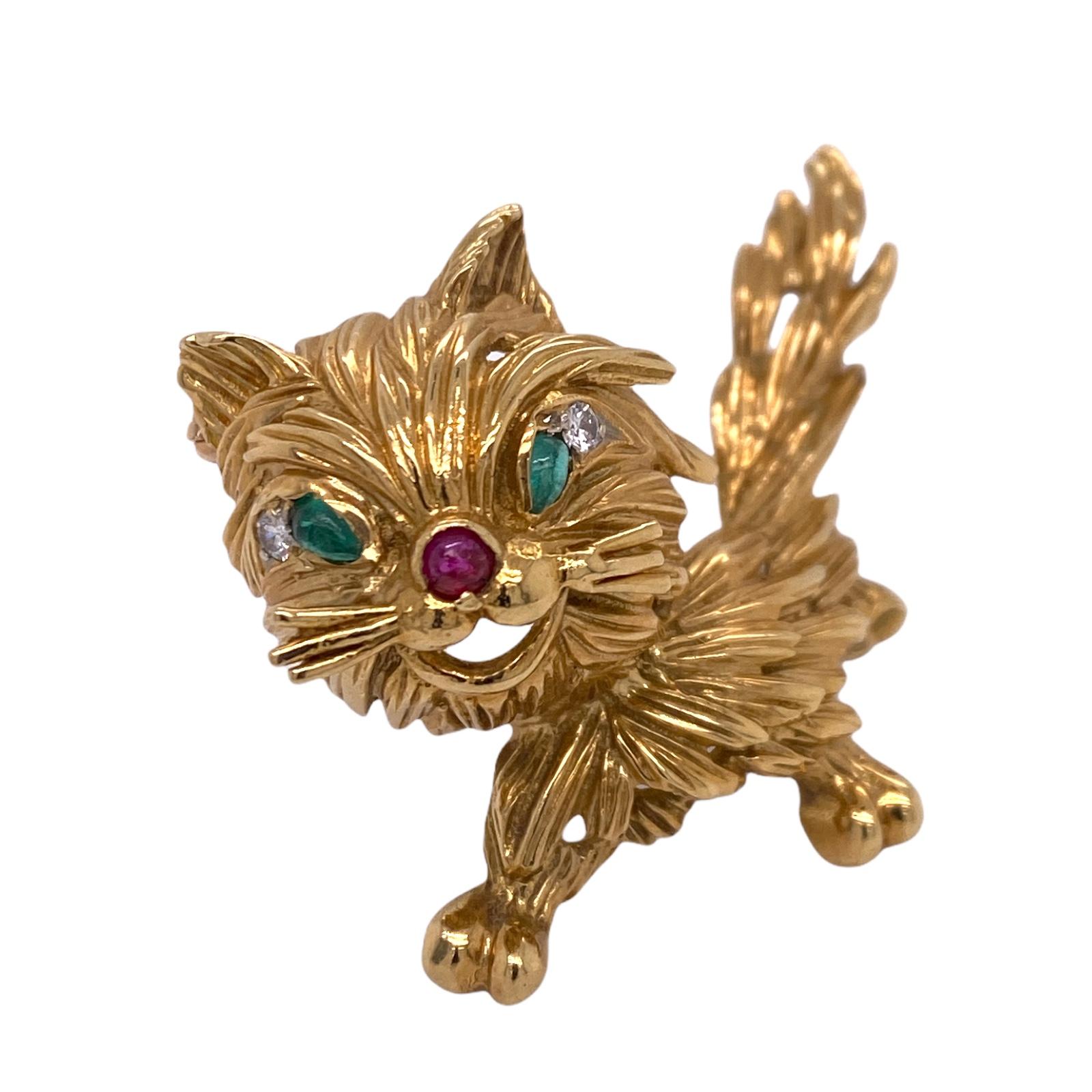 Adorable cat pin fashioned in textured 18 karat yellow gold. The cat features diamond, emerald, and ruby accents, and measures 1.5 x 2.0 inches.
