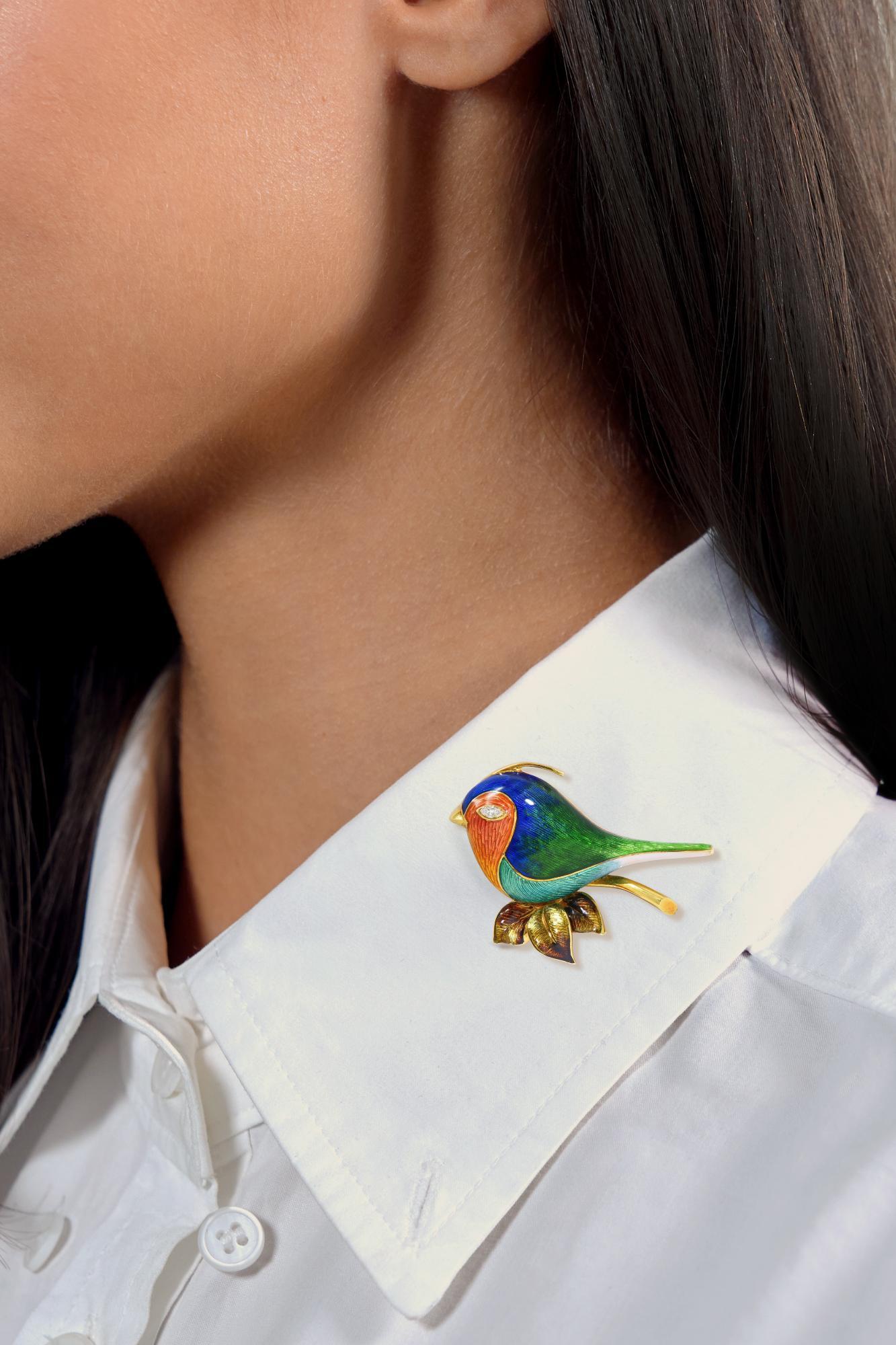 Design/One est un oiseau stylisé en or jaune perché sur une branche avec des feuillages.
Émail basse-taille transparent surmonté d'une gravure linéaire.
Orange, bleu, vert, sarcelle, marron et blanc - perte minime
Accentué par un diamant de taille