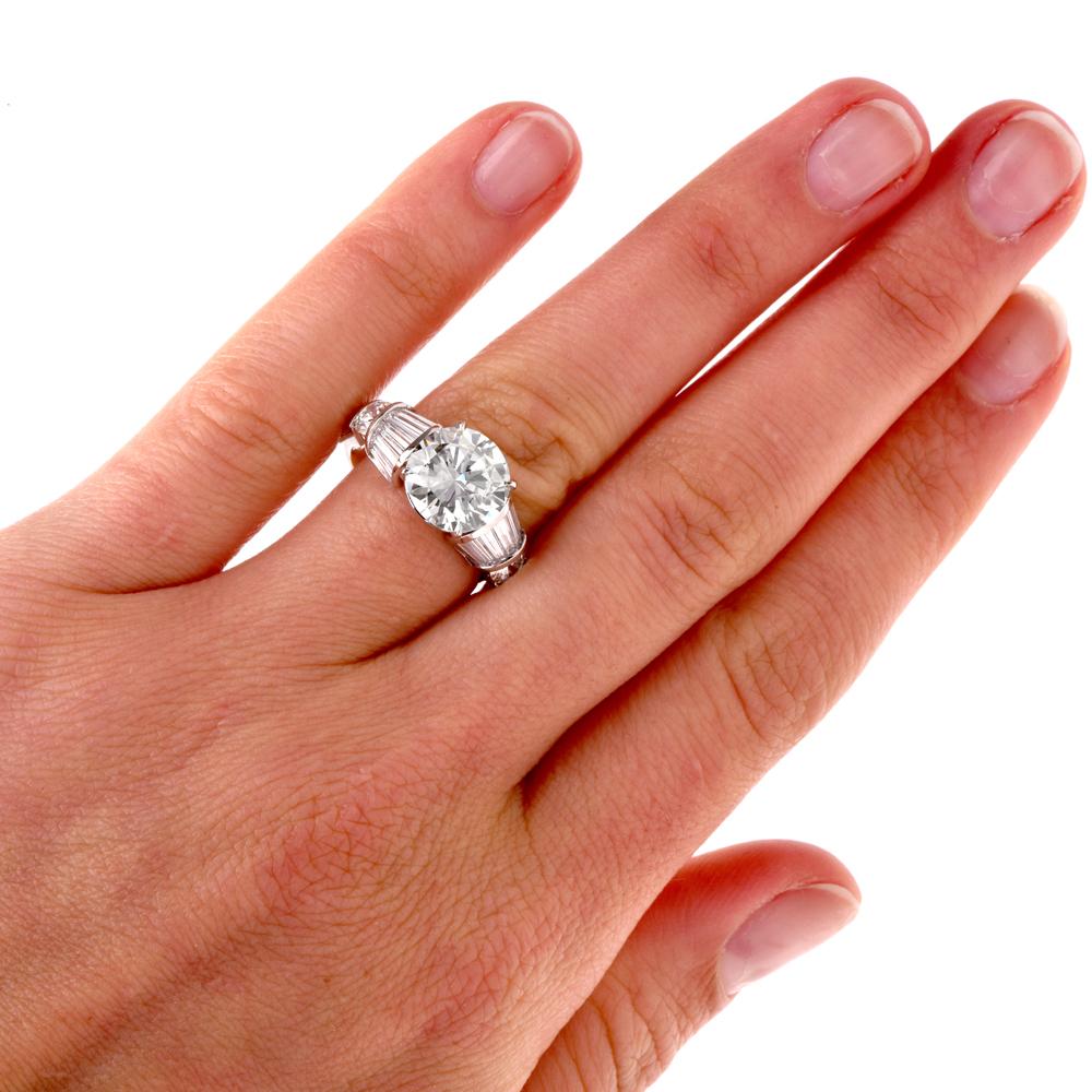 This stunning estate diamond engagement ring is crafted in solid platinum. This ring features a centered round-cut diamond approx. 3.47 carats, J-K color, VVS clarity. Surrounded by 14 baguette and 2 round-cut diamonds approx. 1.60 carats, H-I