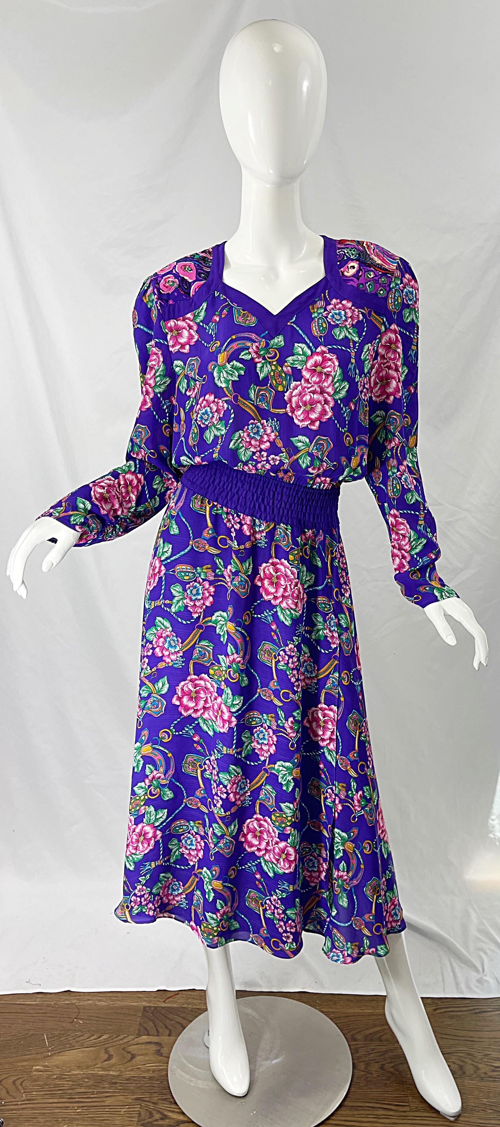 Chic robe midi DIANE FREIS des années 1980 à manches longues, imprimée de fleurs et de bijoux violets ! Il s'agit d'un magnifique fond violet avec des fleurs (peut-être des hibiscus) en rose, et des imprimés de bijoux en bleu turquoise, or, vert