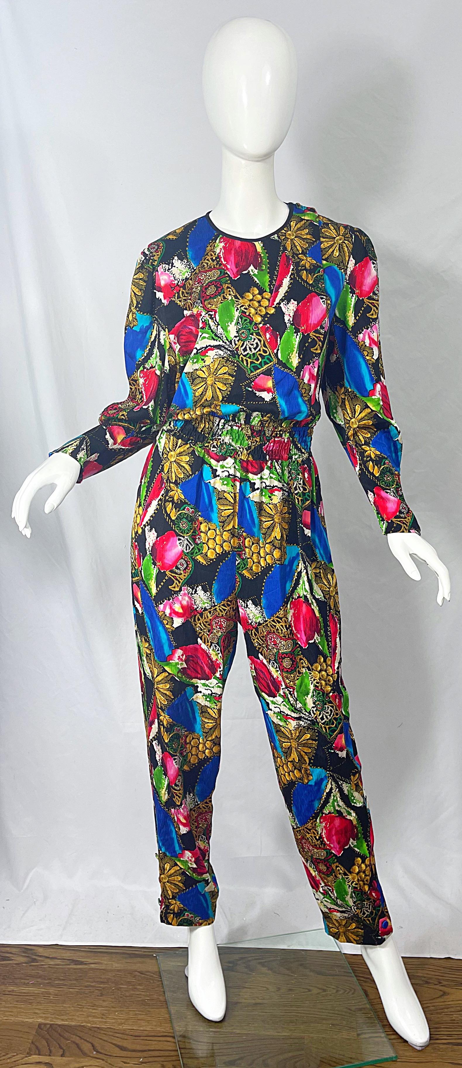 Chic 80S DIANE FREIS jewel and flower print silk jumpsuit ! Features bright colors of blue, green, pink, yellow, black and white throughout. Hidden buttons up the front. Pockets at each side of the waist. Mock buttons at each leg opening. Can easily