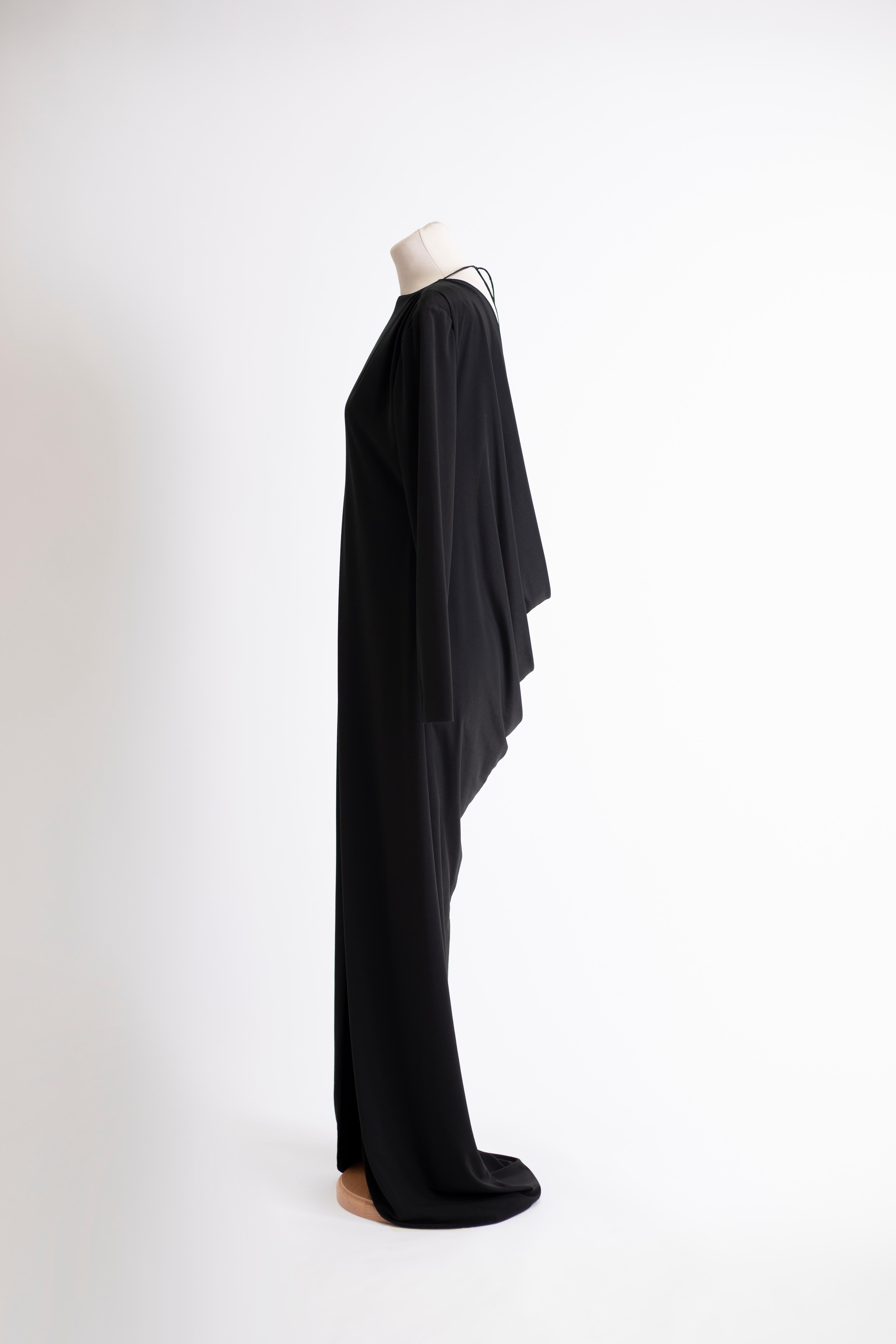 1980s Dimitri Kritsas long black dress with wide shawl neckline and low cut back. Rounded high slit in front with fitted long sleeves.

Evening dress Size: M

Waist: 88 cm
Length: 142 cm
Bust: 100 cm