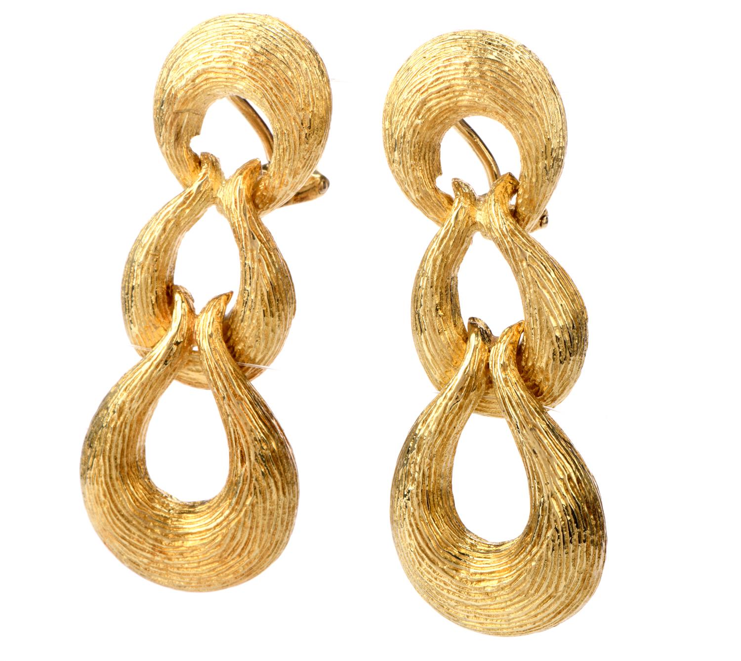 These alluring 1970's earrings were inspired in a triple ring motif featuring a bark finish and crafted in Gold. One ring is layered of the top of the next from top to bottom and each ring was cast in 18K yellow gold. Omega Clip backs secure these