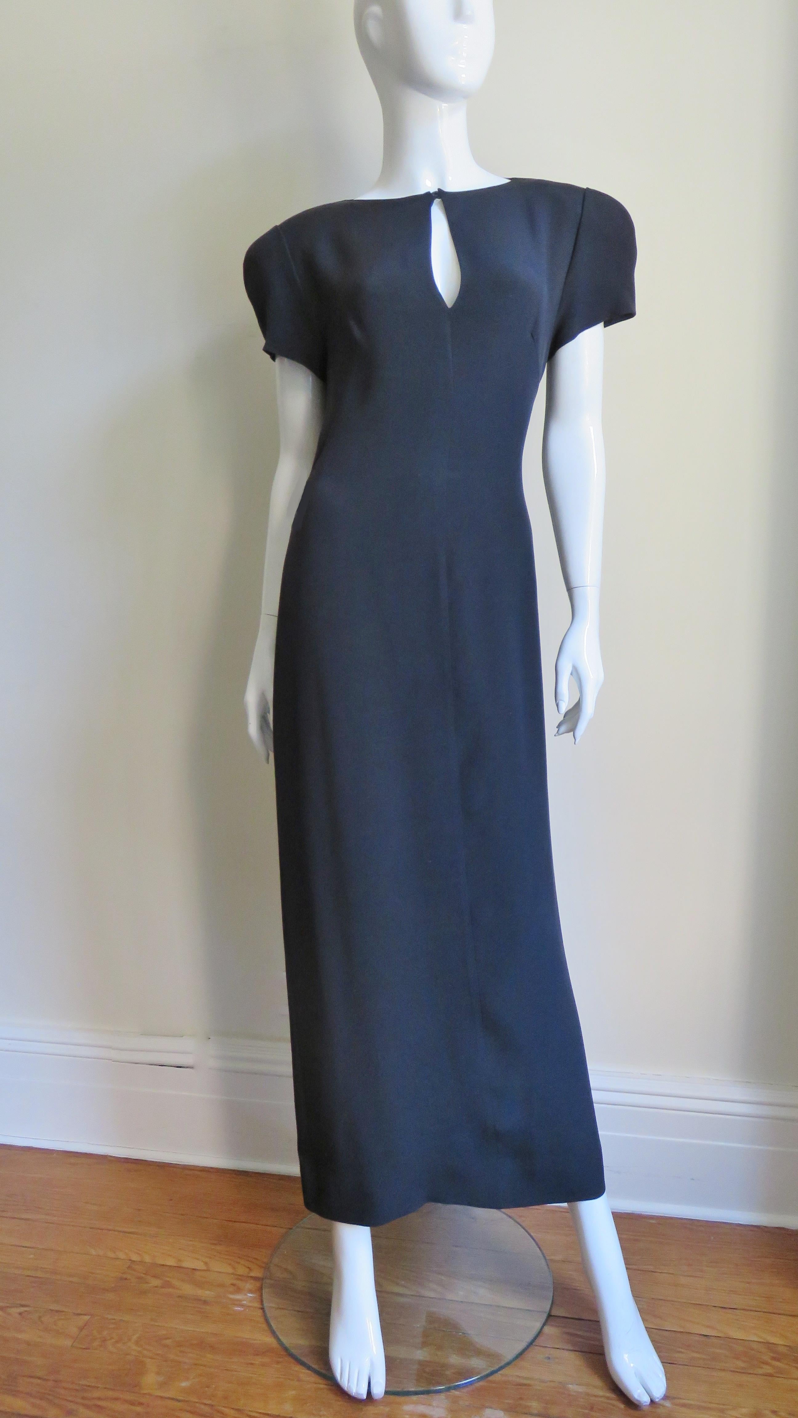 A super rich black silk dress from Krizia.  It has puffed short sleeves and shoulder pads.  The crew neck has a keyhole which closes with a hidden button.  It skims the body and falls straight to the hem.  The main drama is in the back with a draped