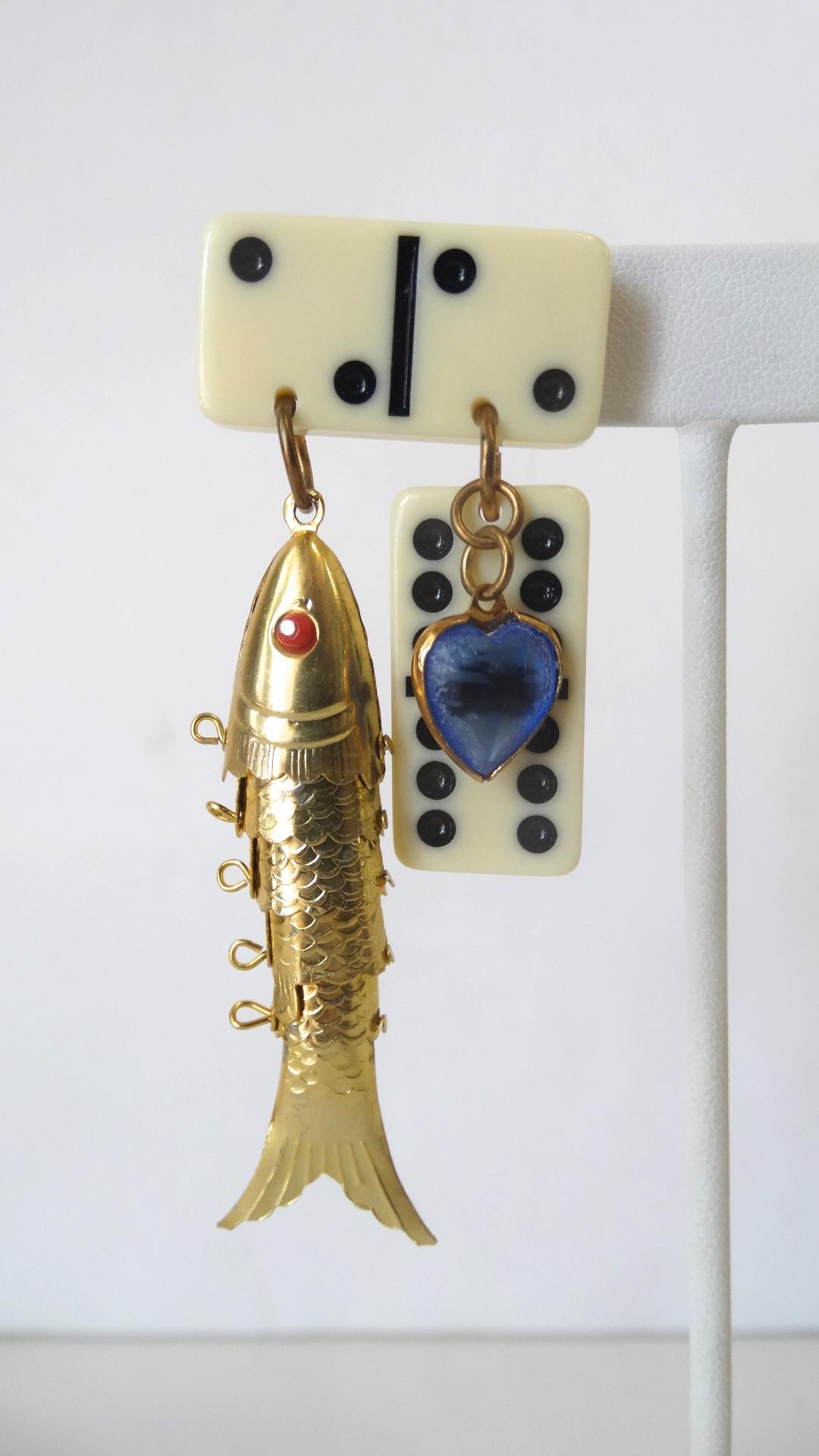 The Most Amazing Earrings Are Here! Circa 1980s, these dangle earrings feature mini dominos, a blue heart charm and a gold plated moveable Chinese fish pendent. The fish pendent includes red eyes and great textural detail. Features pierced backs.