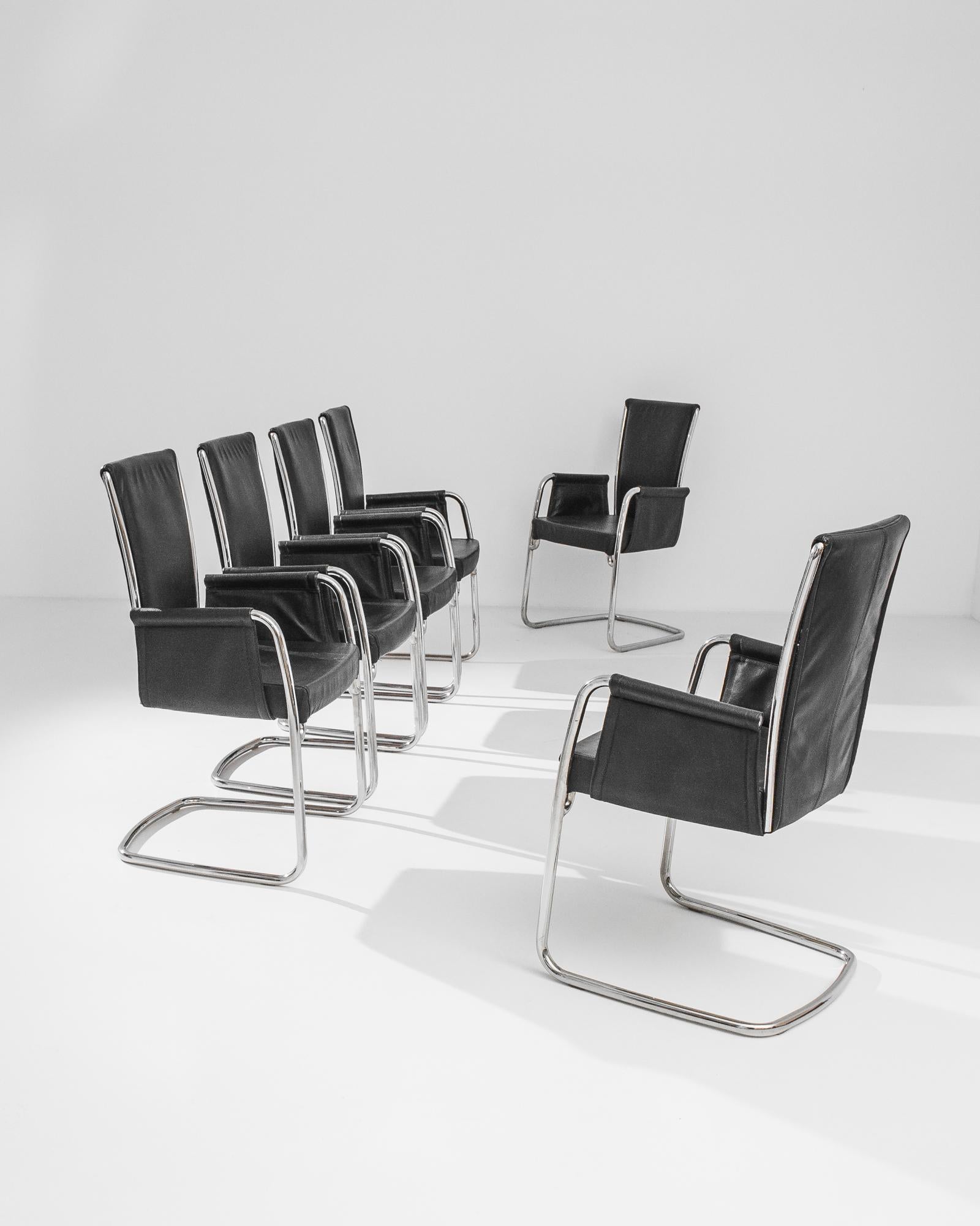 A set of six contemporary dining chairs from 1980s Italy. Made by furniture designers Effezeta, a sleek combination of polished silver metal and black leather creates a modish impression. The cantilevered silhouette has a minimalist poise, creating