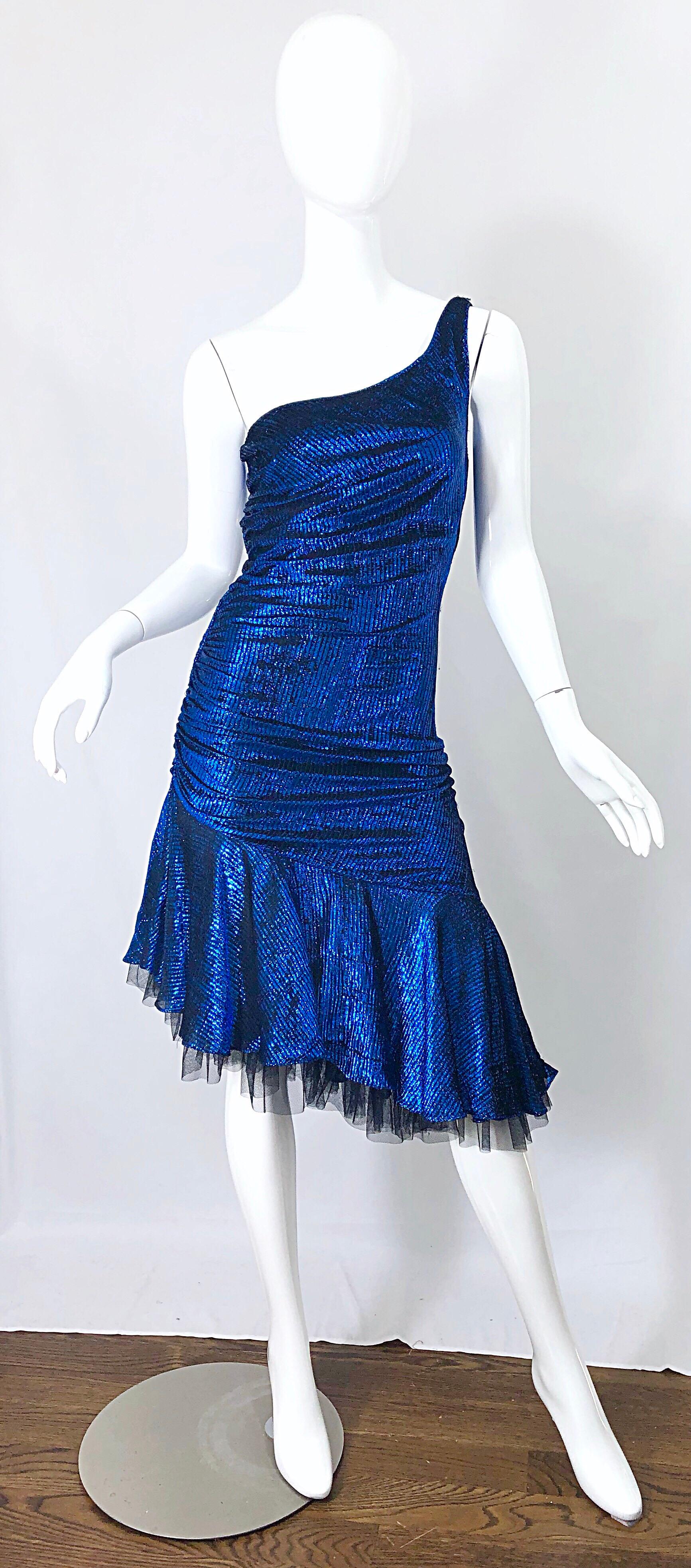 Fabulous 1980s electric blue and black metallic one shoulder asymmetrical hem cocktail dress! Features a fitted body hugging fit, with flattering ruching that covers any 'problem' areas. Black tulle peaks from under the blue skirt. Hidden zipper up