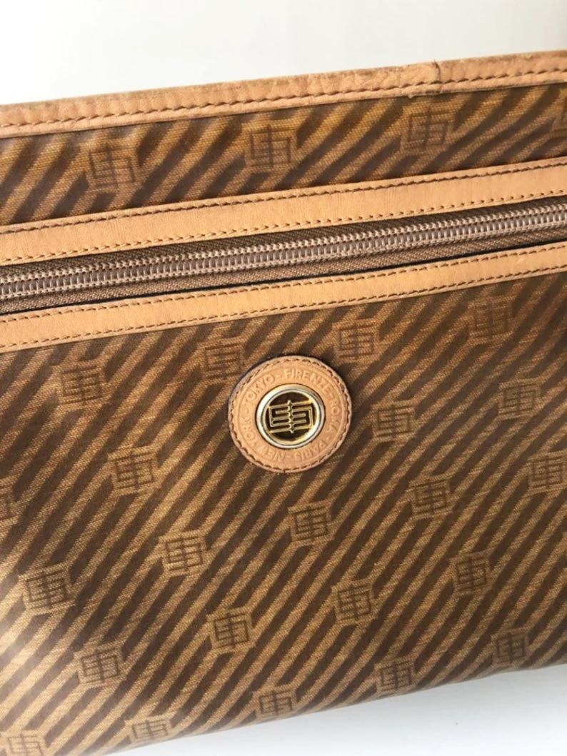 Diese Emilio Pucci Tan Patent Leather Travel Clutch ist ein Vintage-Stück aus den 1980er Jahren, das sowohl Vielseitigkeit als auch Raffinesse ausstrahlt. Sie kann als Clutch, Beauty Case oder Handtasche getragen werden und ist damit ein Must-have