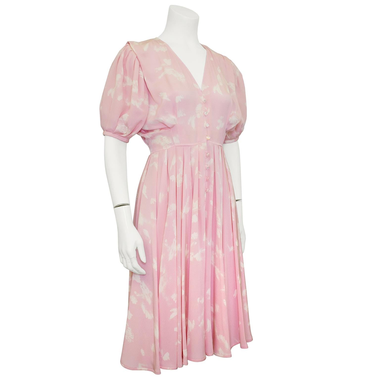 Very sweet Ungaro dress from the 1980s. Coral pink rayon crepe with all over cream coloured abstract splotches. V neckline with buttons down the centre seam. Pleated, gathered and draped short sleeves. Fitted through the waist. Loose, pleated skirt