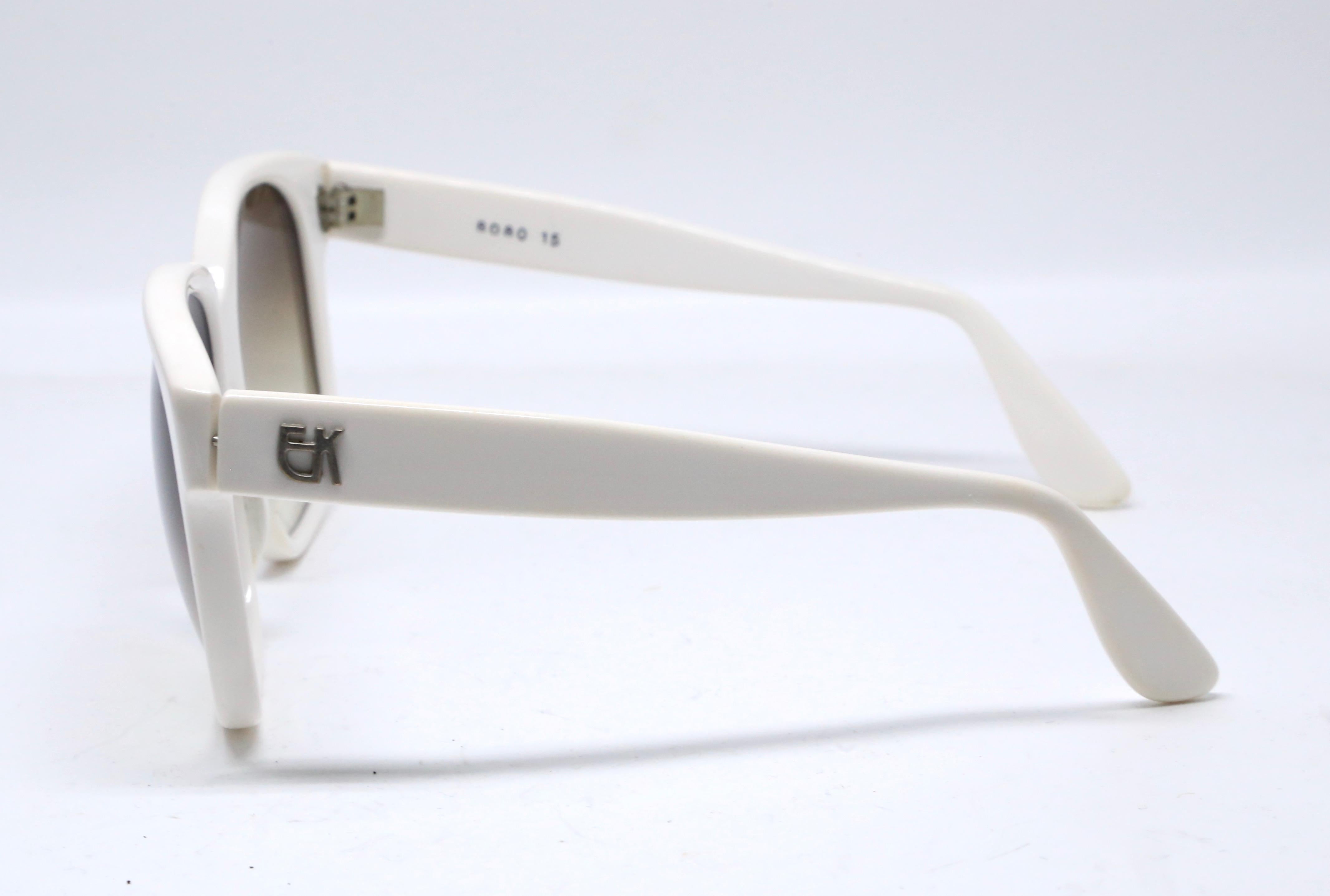 Übergroße, weiße Kunststoffsonnenbrille mit silberfarbenem EK-Logo aus Metall an den Bügeln, entworfen von Emmanuelle Khanh in den 1980er Jahren. Die Rahmen eignen sich gut für ein mittelgroßes oder größeres Gesicht. Ungefähre Maße: 155 mm von