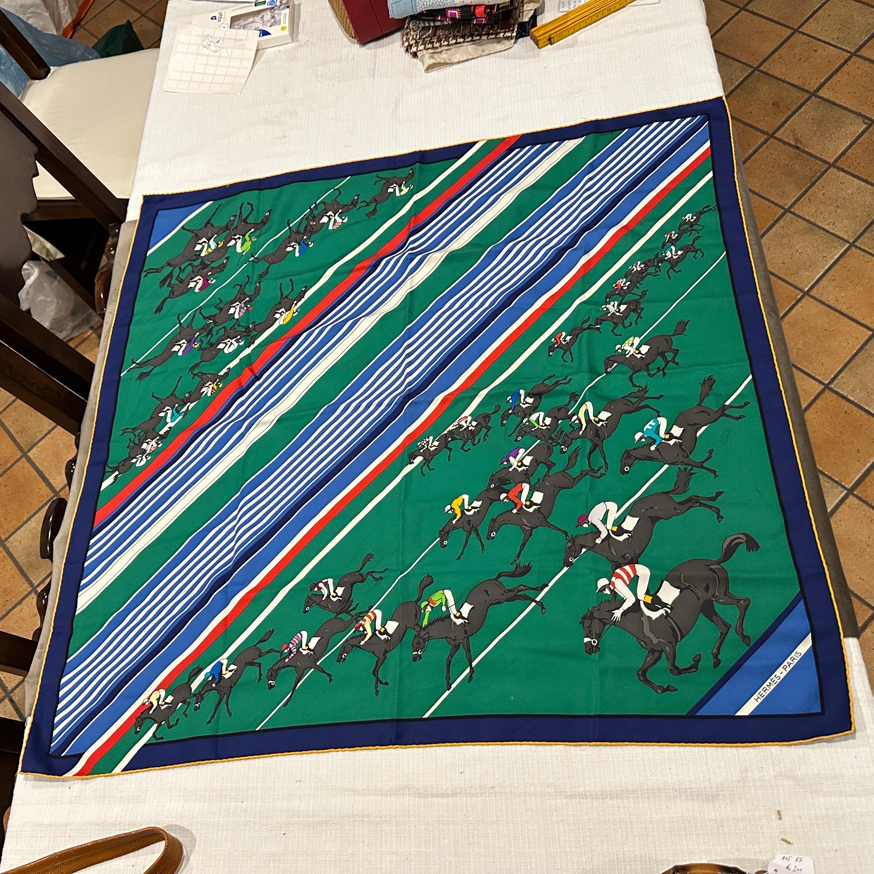 Si tratta di un foulard vintage in seta carré di Hermès degli anni '80 intitolato Les Courses, che significa Le Gare. Presenta una scena equestre dinamica con diversi fantini a cavallo, congelati a metà del galoppo, creando un forte senso di