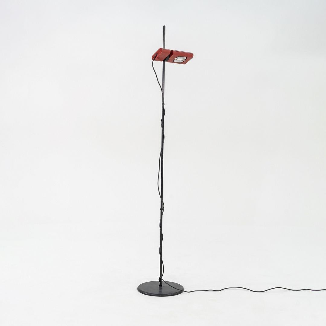 Ésta es una lámpara de pie posmoderna, modelo Aton Terra, diseñada por Ernesto Gismondi para Artemide en la década de 1980. La pieza presenta una pantalla rectangular roja ajustable, y tiene un largo y delgado vástago de acero. La potencia es negro