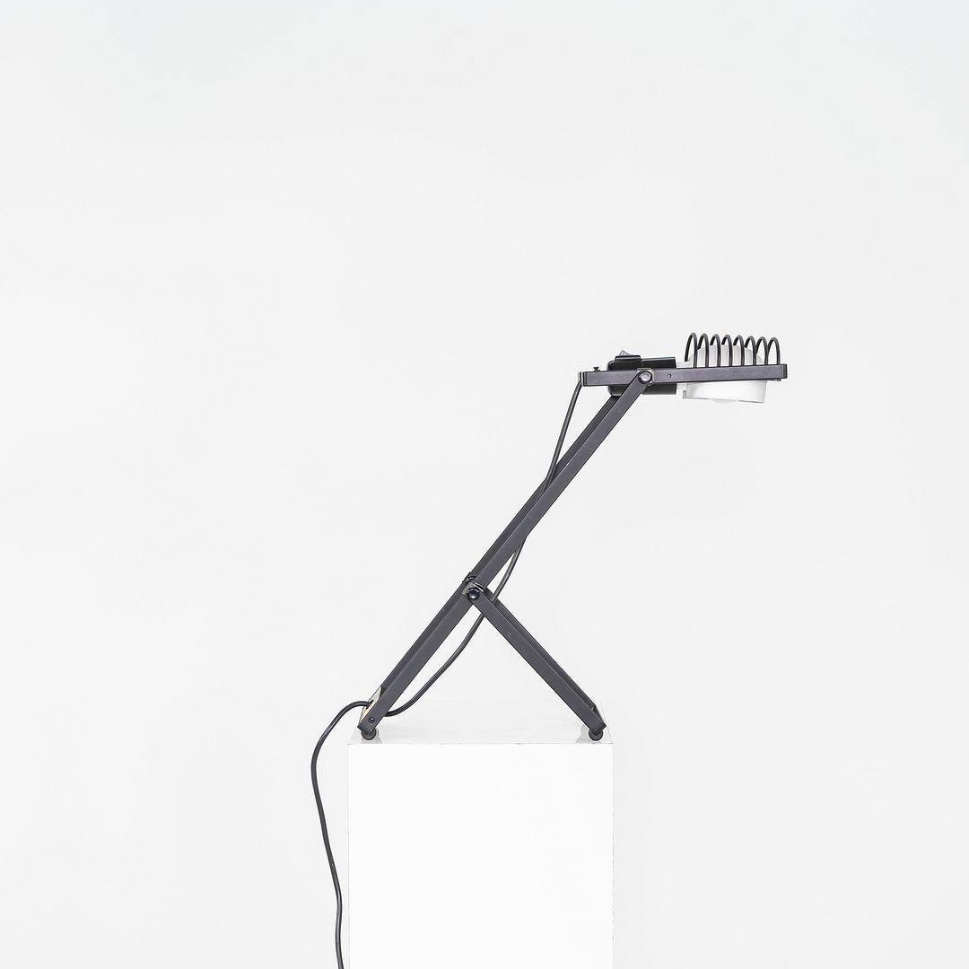 This is a Sintesi Lamp, originally designed by Ernesto Gismondi in 1976. This particular example was produced by Artemide in Italy in the 1980s. The lamp features a black enameled metal shade mounted on an adjustable arm and stem, allowing