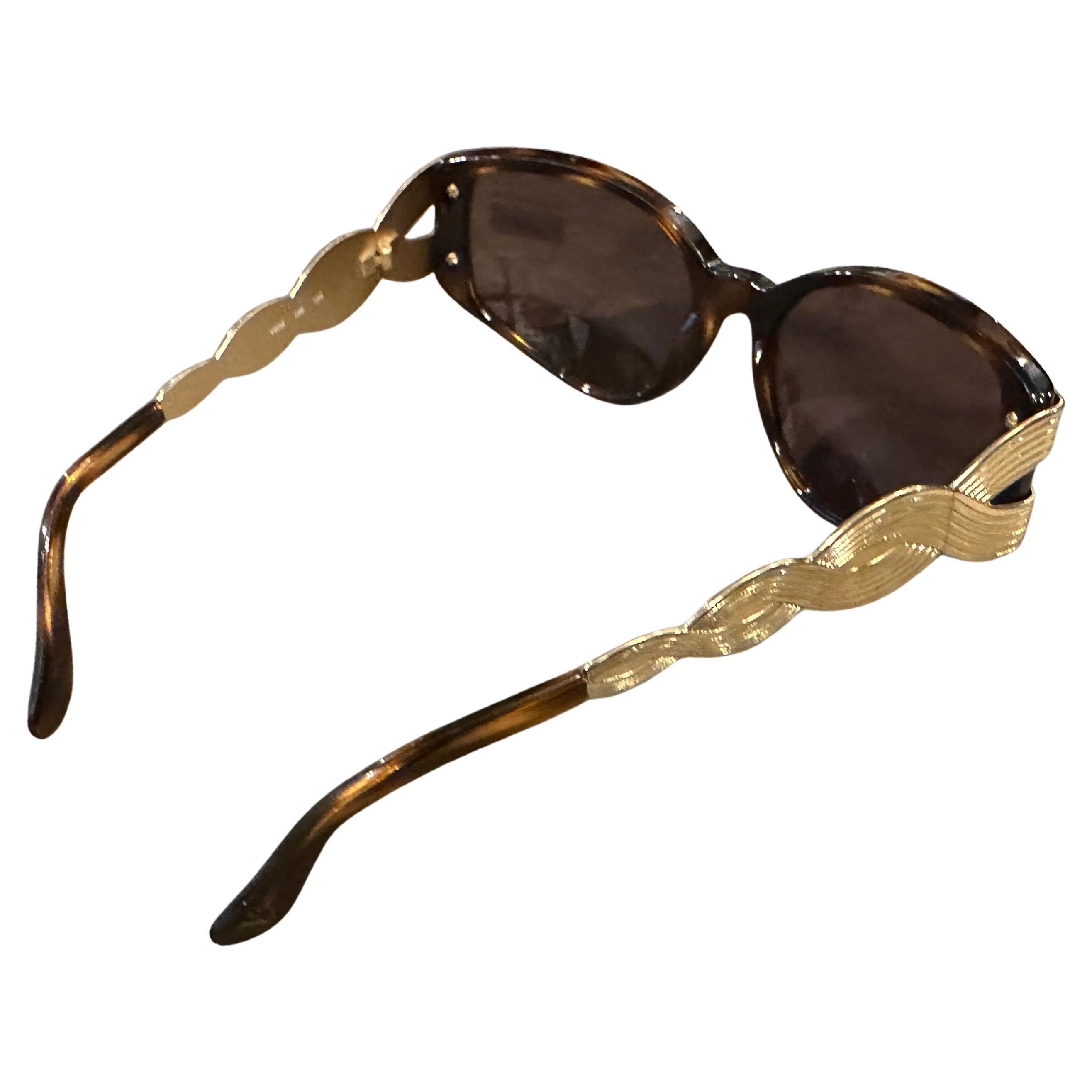 Diese außergewöhnliche Vintage-Sonnenbrille von Valentino aus den 1980er Jahren verkörpert den opulenten und glamourösen Stil dieser Zeit. Diese übergroßen Rahmen kombinieren raffiniertes Schildpattimitat mit auffälligen skulpturalen Messingdetails