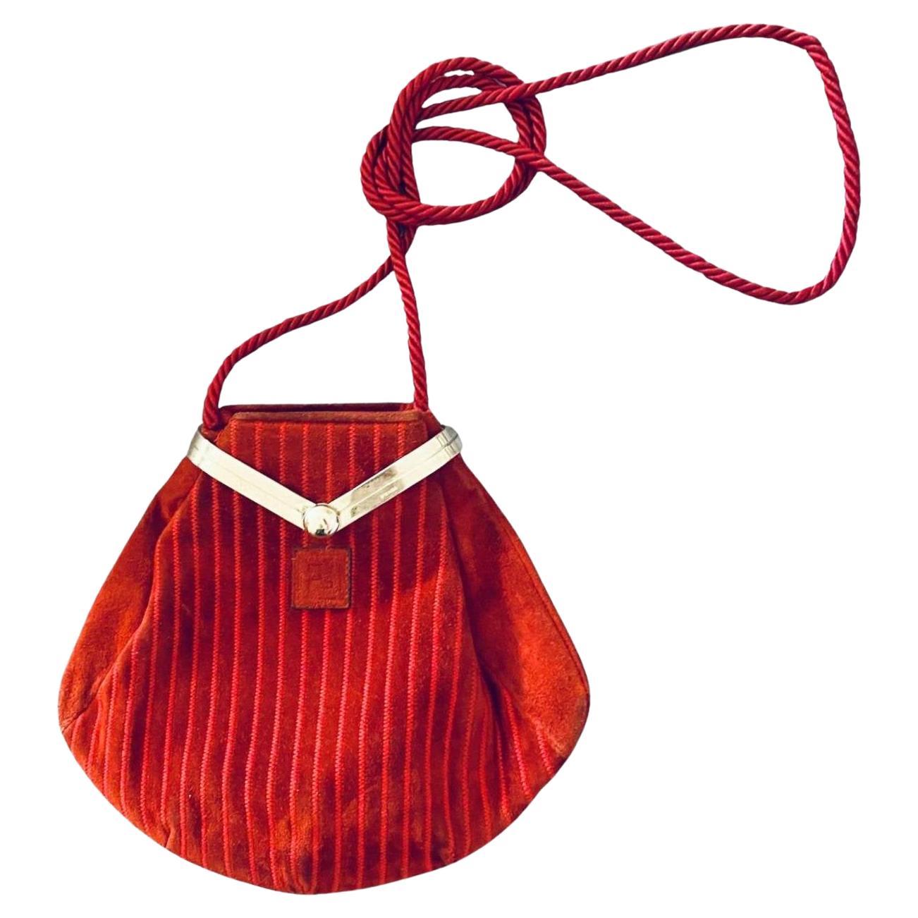Ce sac Fendi des années 1980, unique en son genre, présente un extérieur en daim rouge avec des détails en zigzag et une fermeture à pochette dotée d'une élégante pièce métallique gravée du logo Fendi. A l'intérieur, le sac accueille une doublure en