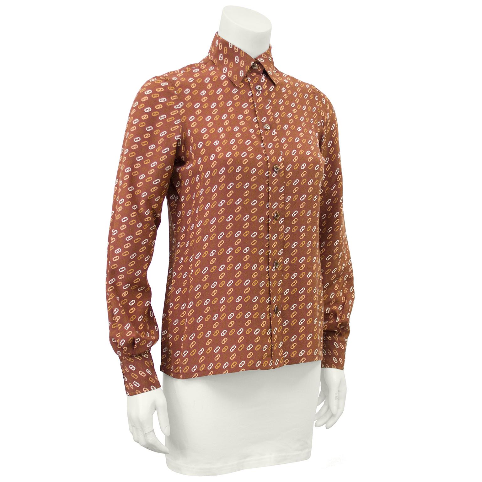 Beautiful 1980s Ferragamo tan silk blouse with an all over print of tan, brown, cream and beige FF link Ferragamo logos. Free of any stains or holes, the blouse fastens up the front with small plastic brown buttons. and buttoned cuffs. In excellent