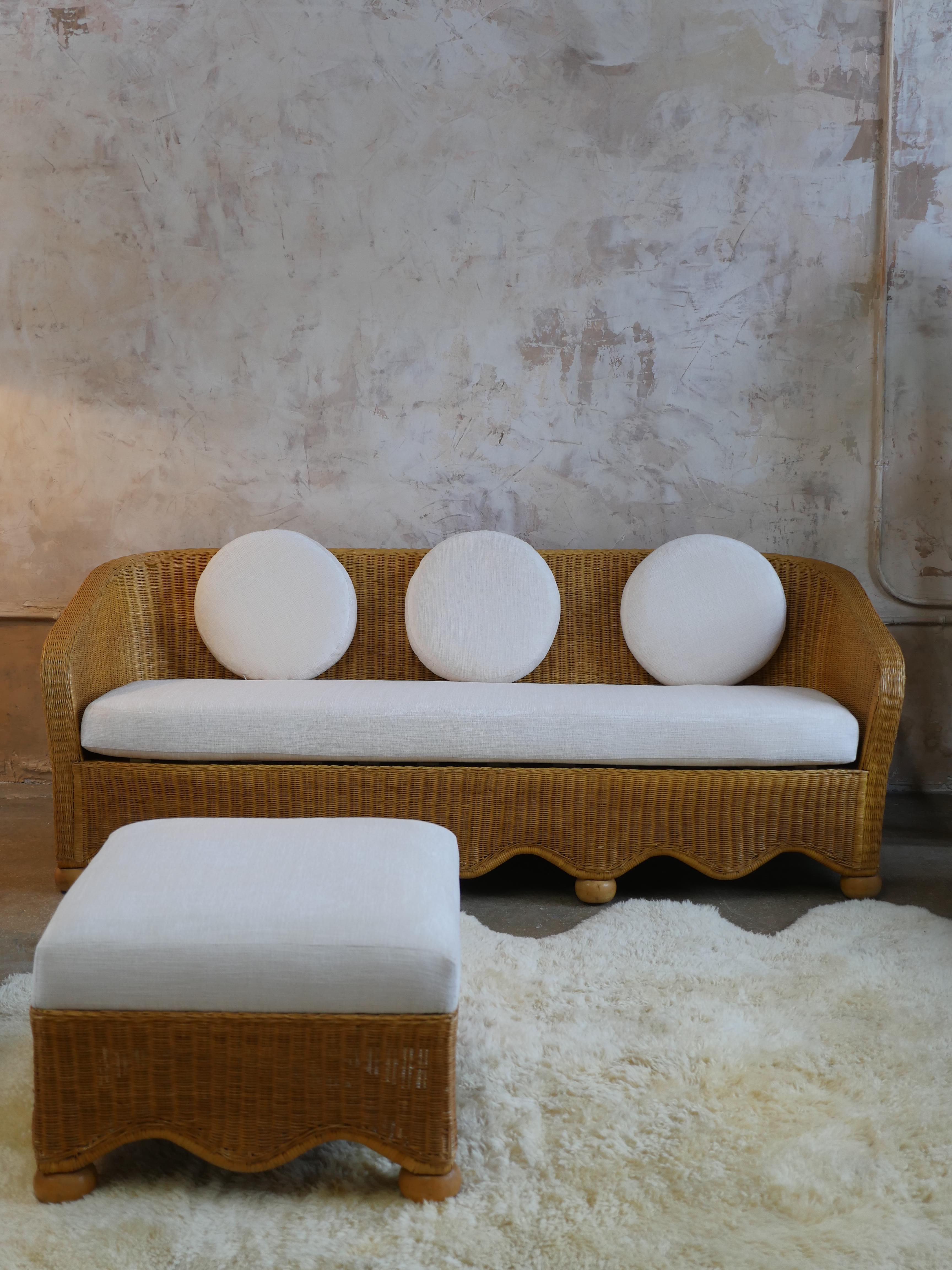 Introducing our 1980s rattan scalloped sofa with wooden ball feet which has been beautifully reimagined with new Holly Hunt off-white chenille fabric, giving the sofa a true embodiment of vintage elegance and refined taste. We've taken great care to