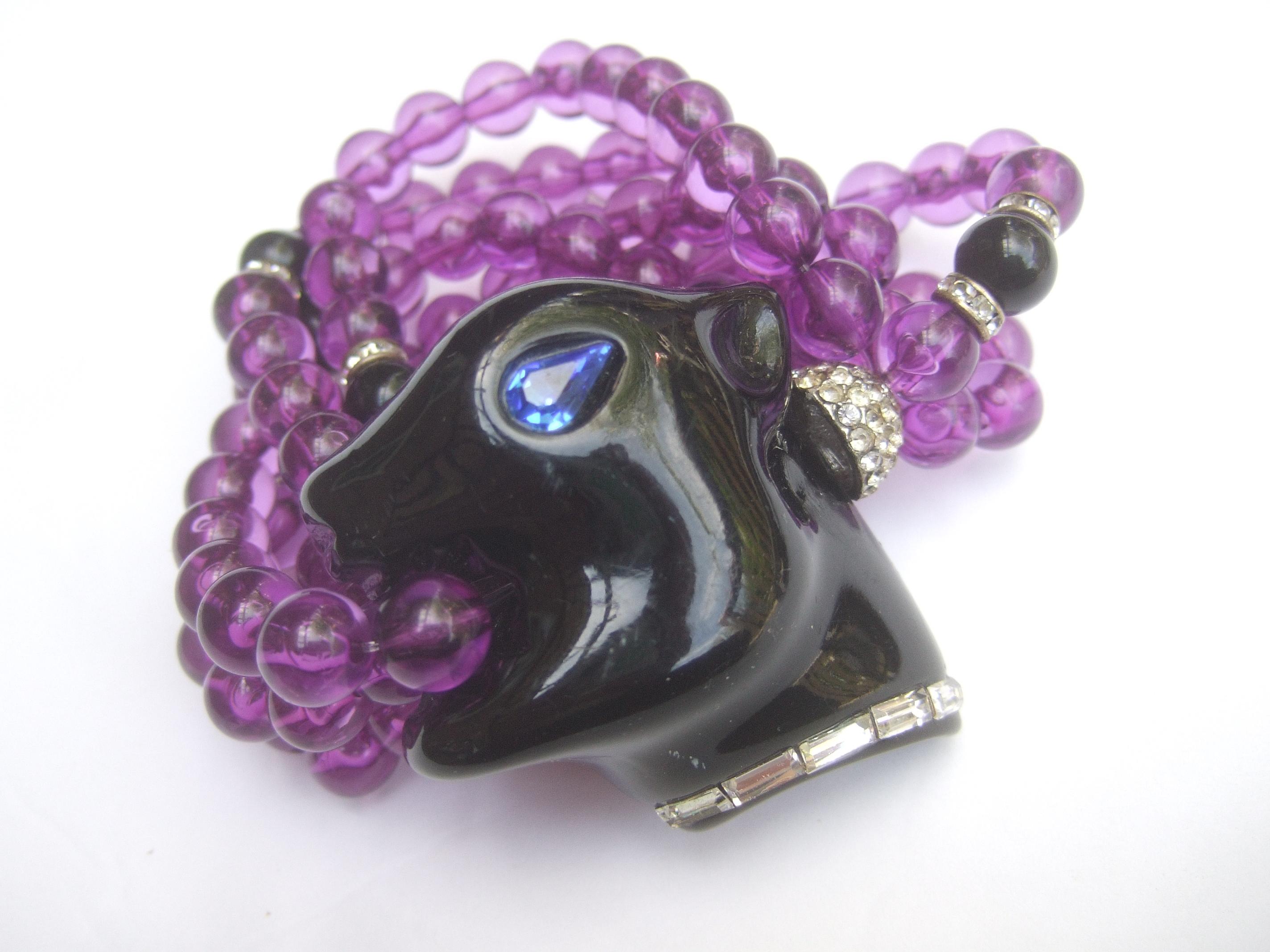 1980s Exotic figural panther's head jeweled crystal resin beaded bracelet. Small Size 
The unique bracelet is designed with a smooth black lucite panther's head
with a sapphire blue color crystal eye. Accented with a clear baguette crystal 
collar.