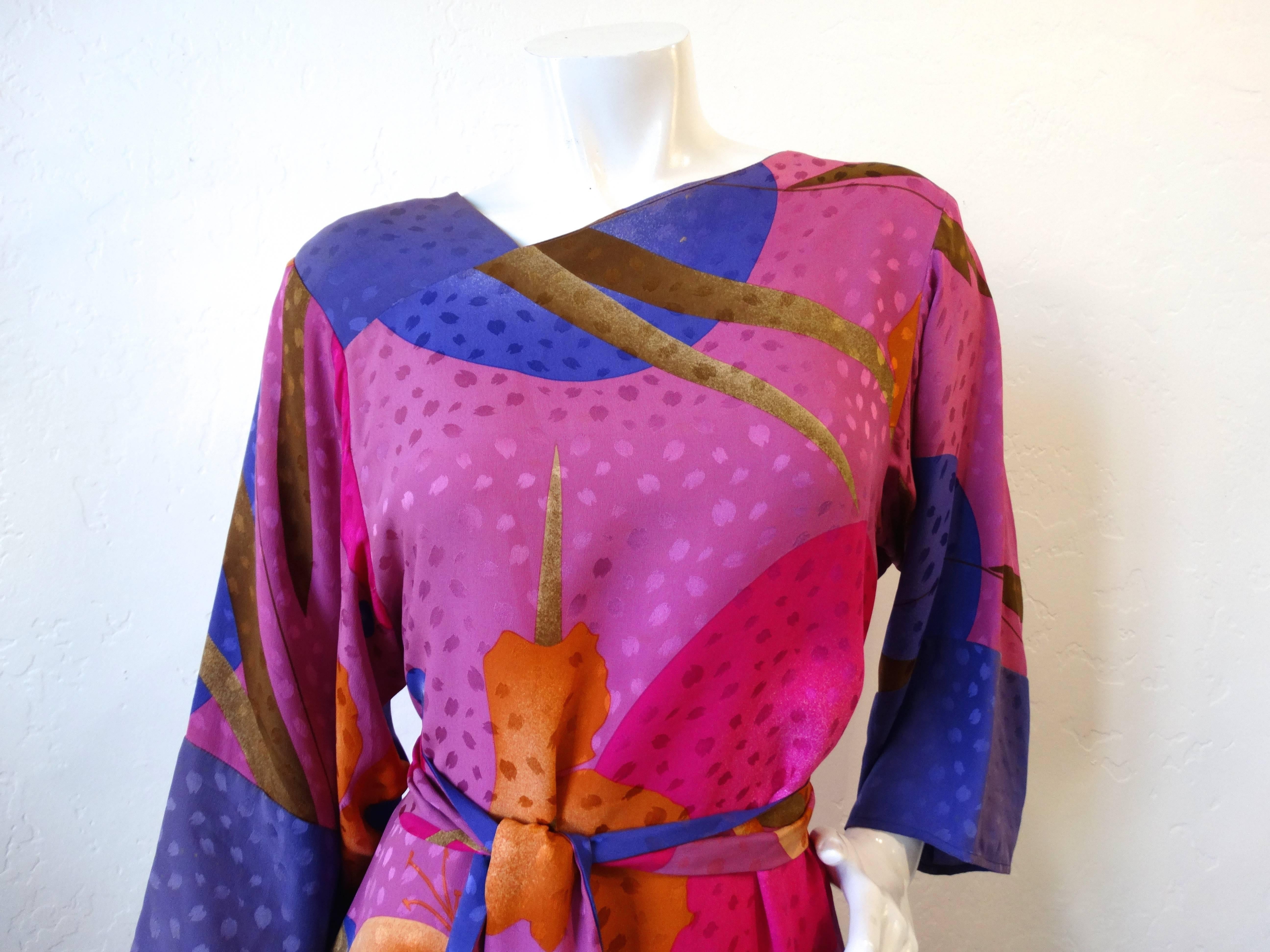 The sweetest little Flora Kung dress circa 1980s! Made of a breezy, soft silk fabric printed with an abstract lily inspired pattern in shades of magenta, violet and orange. Unique asymmetrical neckline slopes toward the right shoulder. Cinches in at