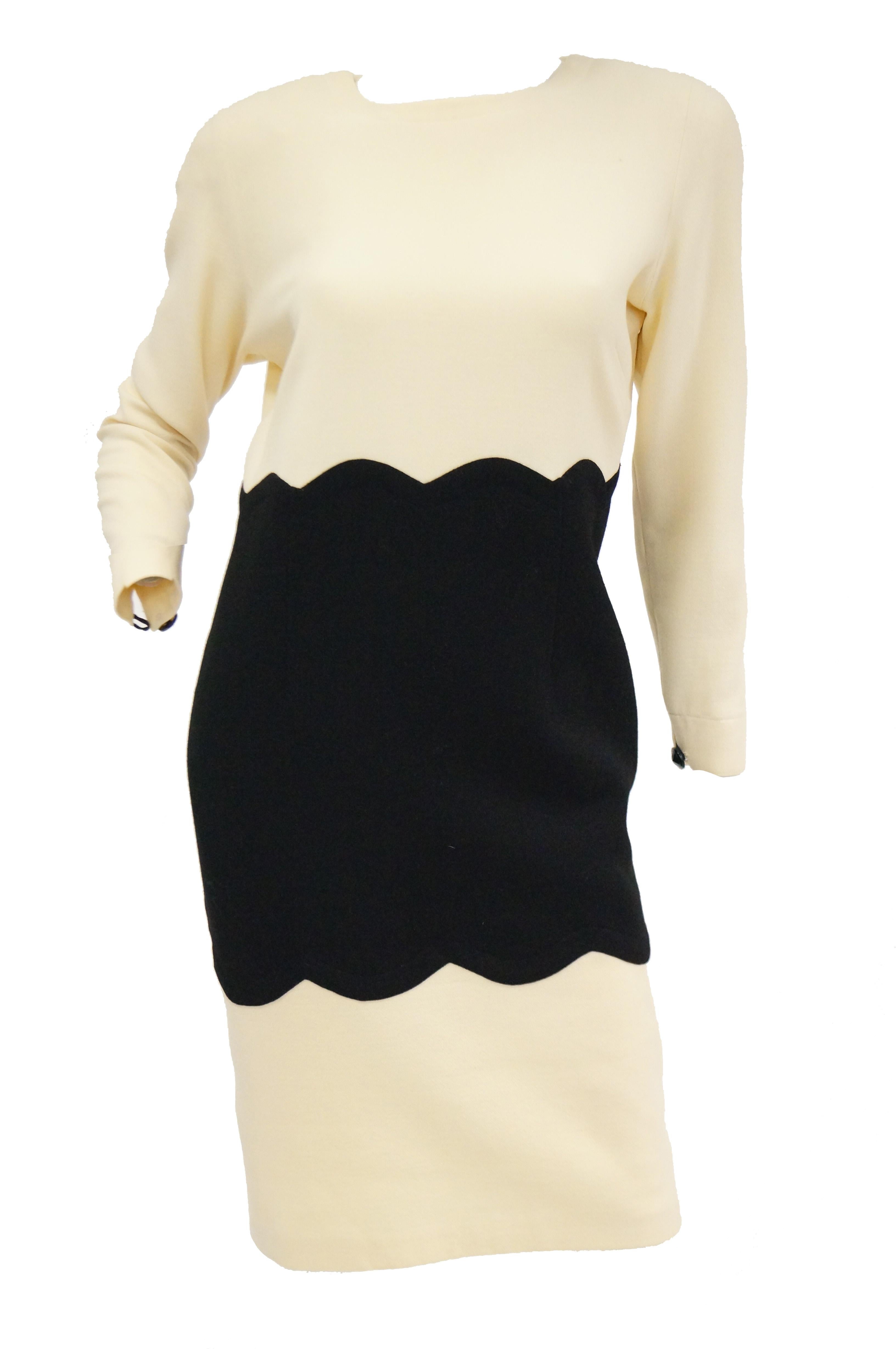 Elegant yet playful cream and black color blocked dress suit set by Amen Wardy. The ensemble is composed of a long sleeve knee - length dress, and a long sleeve, hip - length blazer. The dress has a wide jewel neckline, structured shoulders, and
