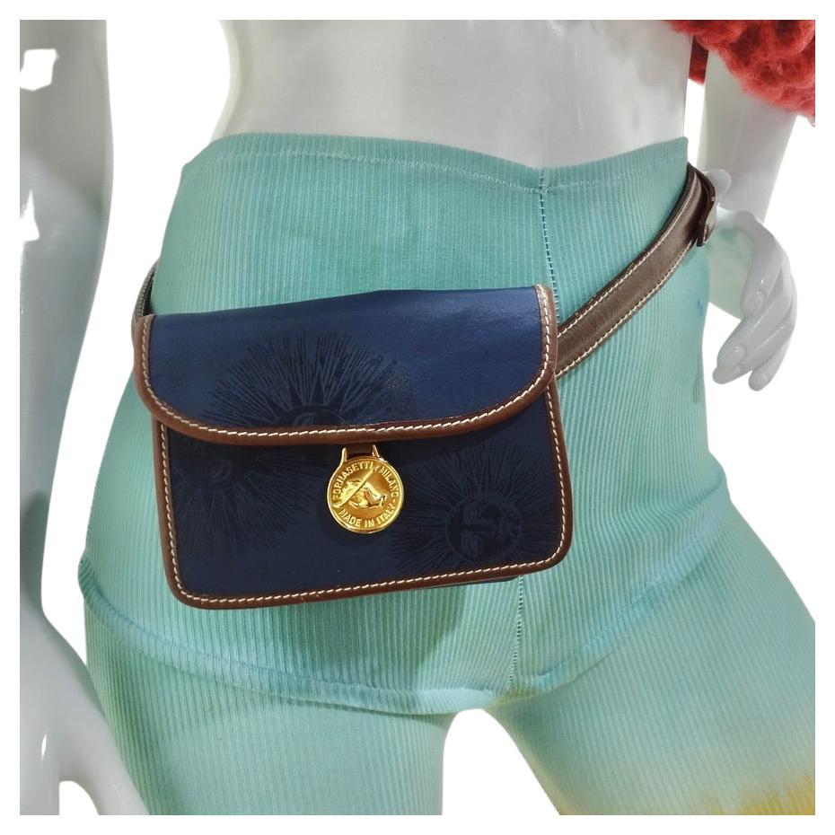 Classic and versatile Fornacetti belt bag circa 1980s! Super wearable messenger style belt bag in e great neutral navy blue color with gold hardware and brown leather accents. Look closely and notice the gorgeous sun print embroidered onto the