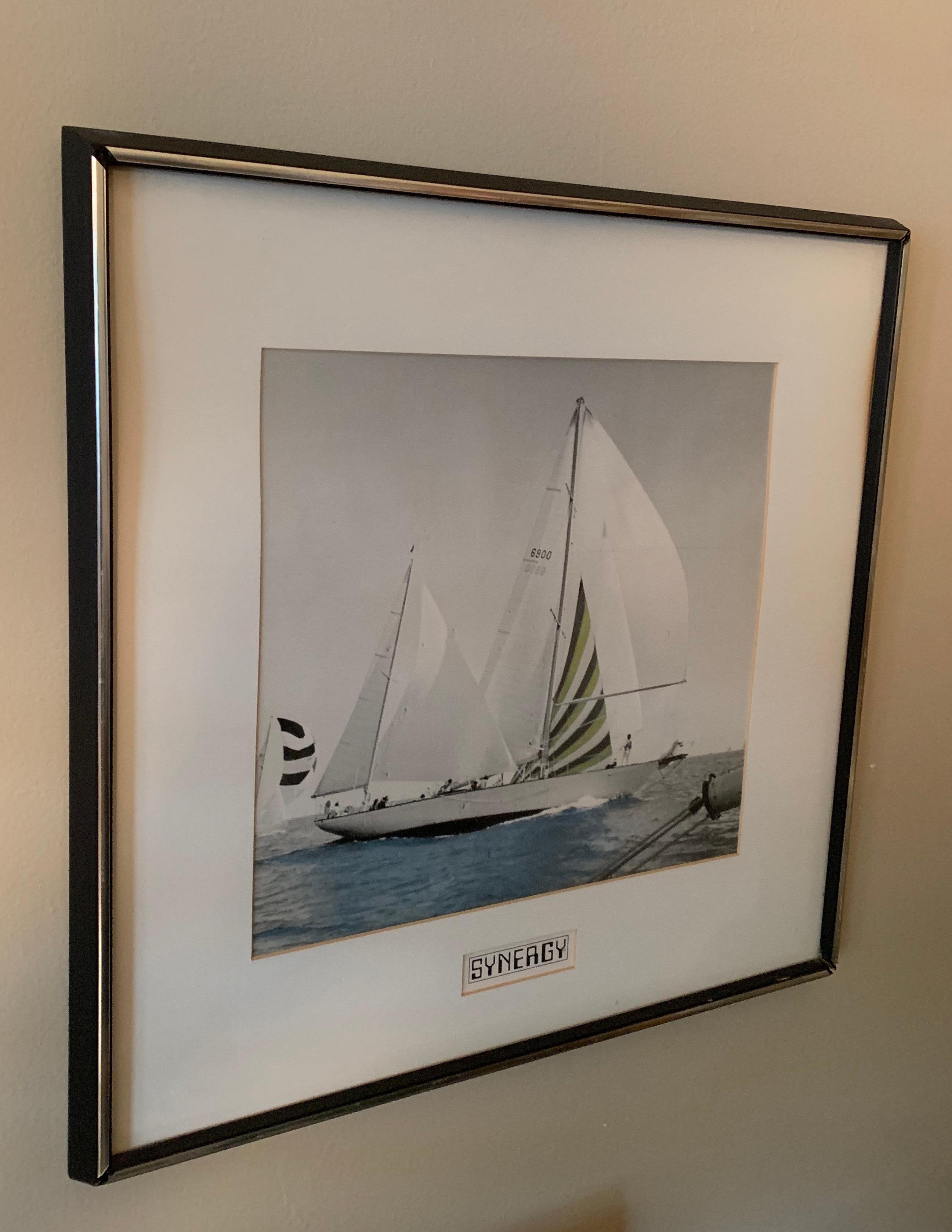 A vintage color photograph of the Synergy sailboat, USA, circa 1980. 

Custom matted and framed in a period black wood with chrome trimmed frame. 

Photo in VG/Very Good condition; light vintage wear to frame.

Overall size: 20-7/8 inches x