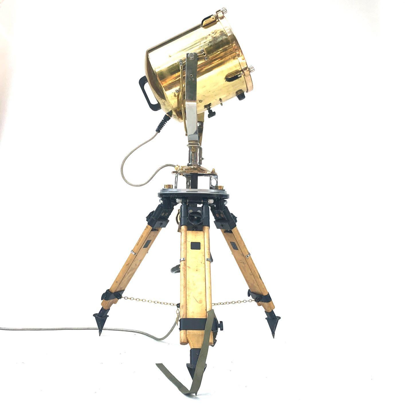 A reclaimed retro industrial British brass search light manufactured by Francis in 1980s coupled with a Russian military gyroscope tripod.

There is a circular handle inside the tripod which is used to mechanically pan and tilt the lamp.
