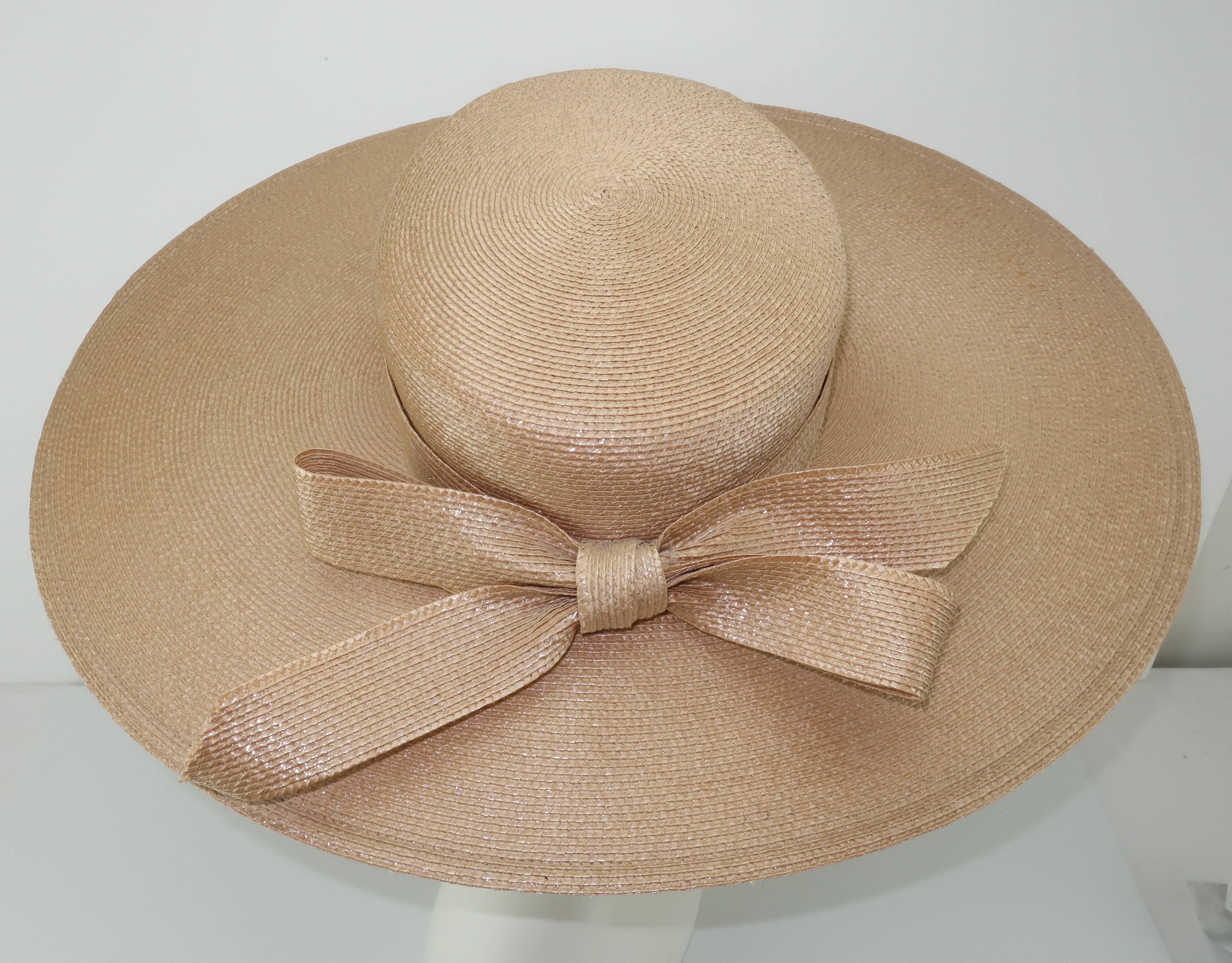 This Frank Olive straw hat for Saks Fifth Avenue has a classic wide brimmed silhouette with a subtly unique oval design reminiscent of 1920's styles.  The flesh tone straw has a coating which creates an understated shimmer providing a formality to