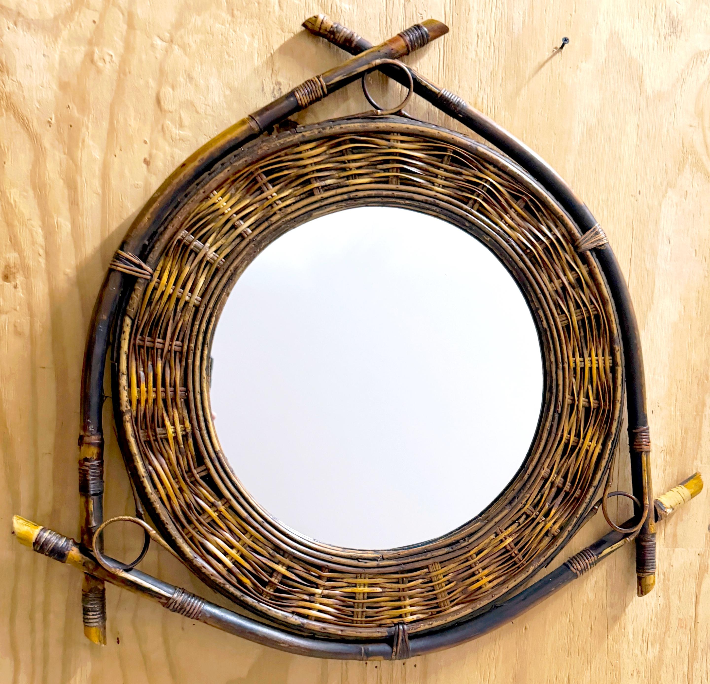 1980s French Bamboo, Woven Rattan, and Willow Shield Mirror

A striking piece that brings a touch of modern tribal design to any interior. This unique mirror features three bent bamboo rods wrapped in willow and reed, elegantly holding a circular