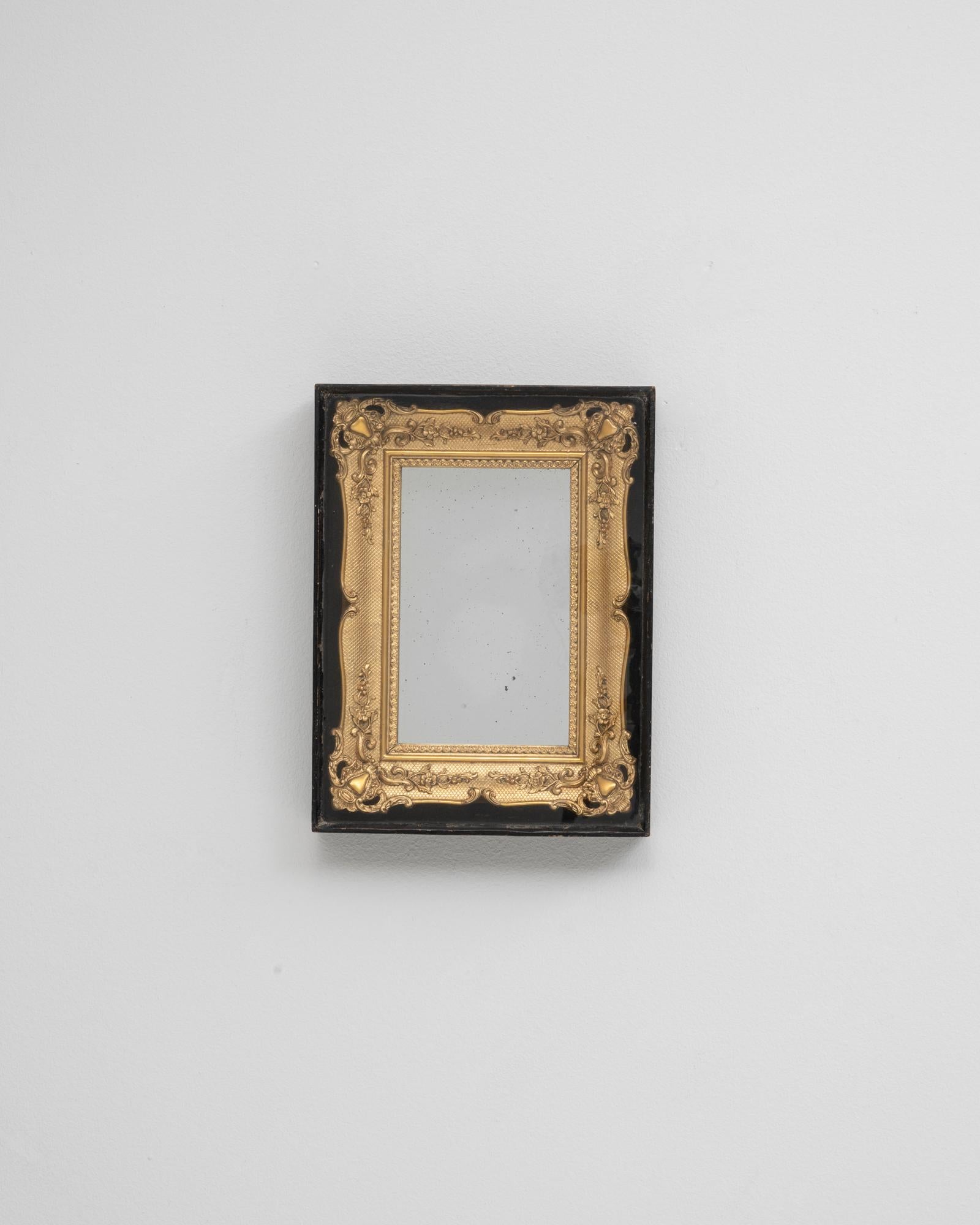 Questo specchio francese dorato degli anni '80 in una teca di legno fonde motivi decorativi classici con uno stile di presentazione raffinato. La cornice dorata, riccamente ornata con fogliame a scorrimento, dettagli floreali e superfici